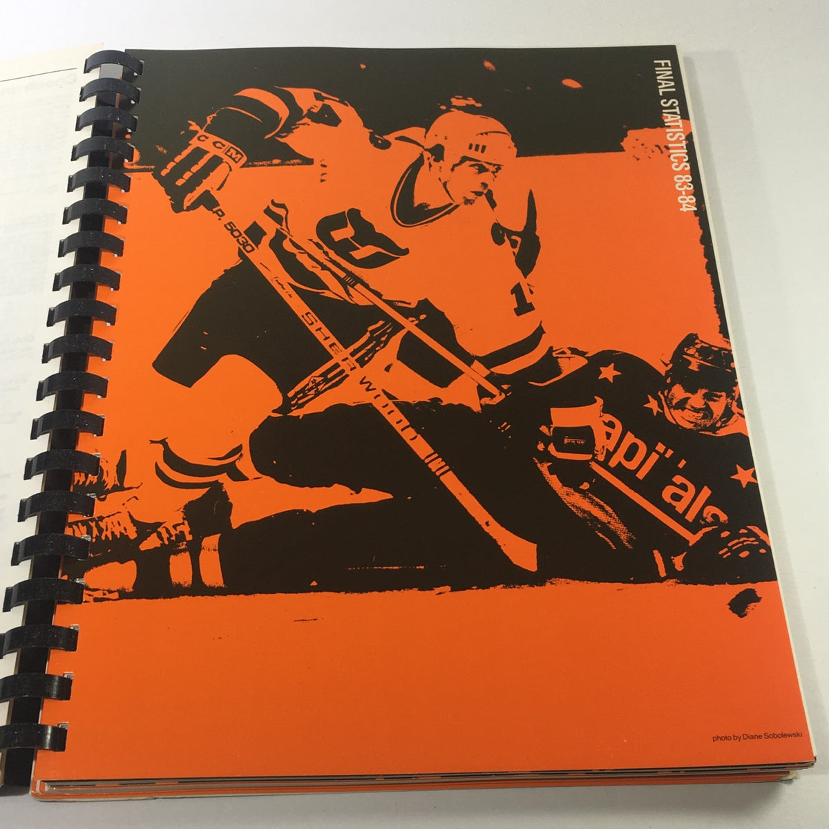 Cover of the VTG NHL Official Guide & Record Book 1984-1985, displaying an action shot of two hockey players, with a bold orange background.