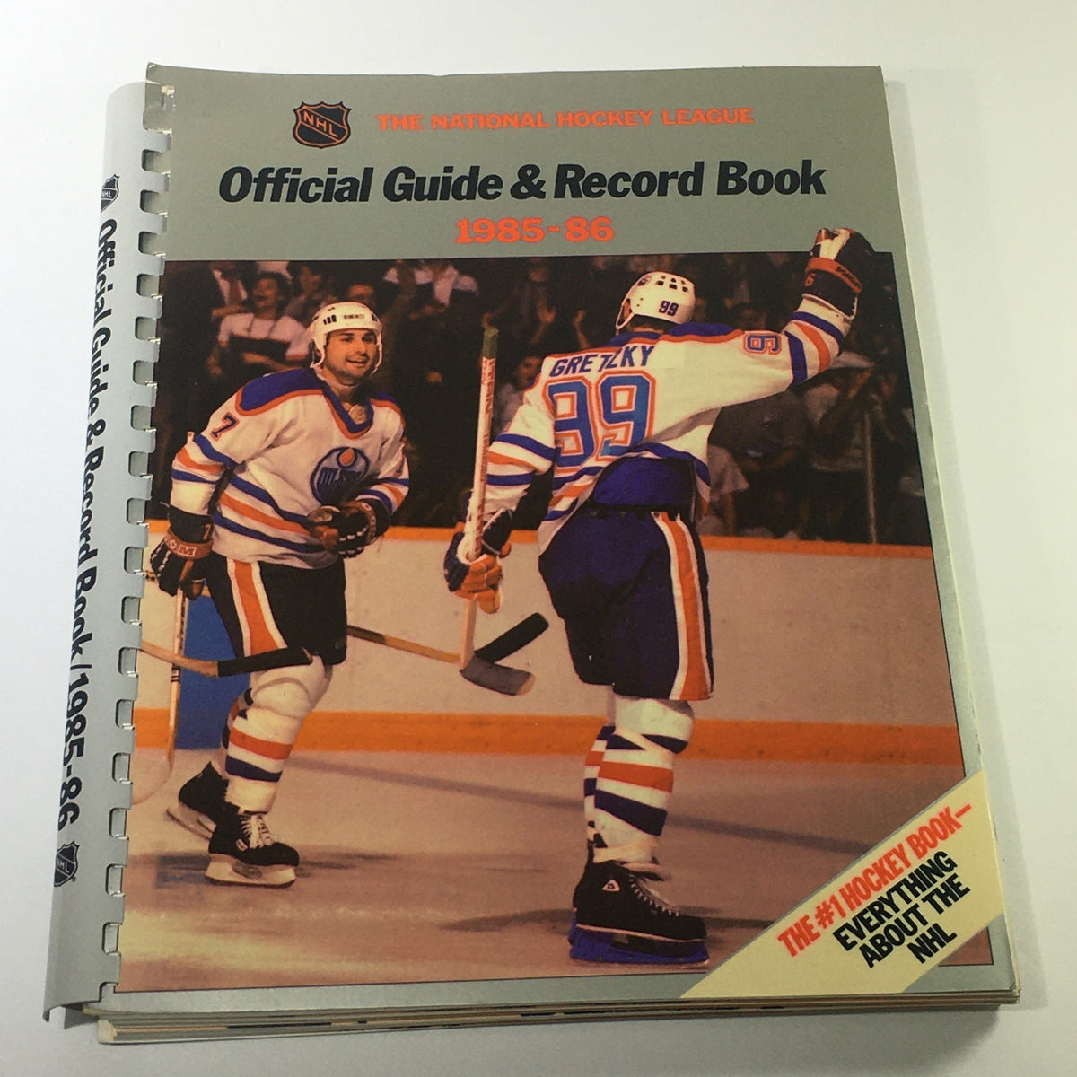 VTG NHL Official Guide & Record Book 1985-1986 Edmonton Oilers featuring players celebrating on the cover with Wayne Gretzky wearing jersey number 99 during a game.