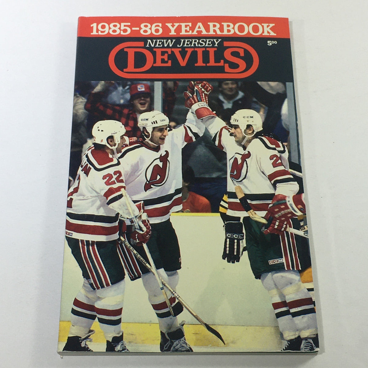 1985-86 Yearbook of the New Jersey Devils featuring Doug Sulliman, showing players in team jerseys celebrating a goal.