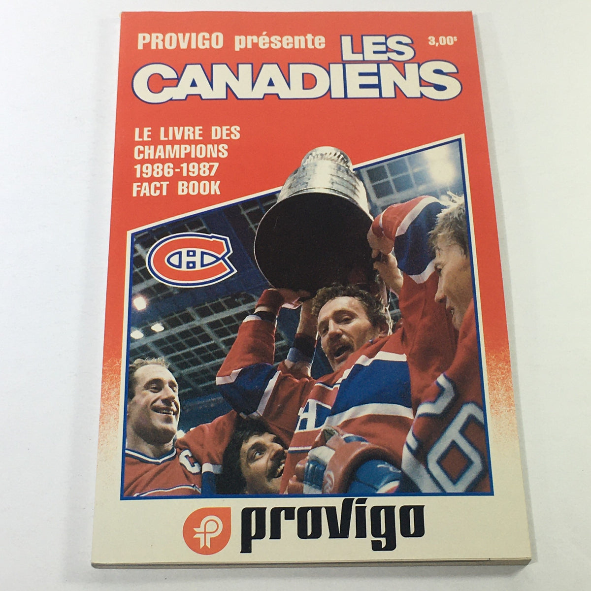 Cover of the VTG NHL Official Fact Book 1986-1987 - Les Canadiens, featuring a celebration scene with players holding the trophy, vibrant colors, and the Provigo branding.
