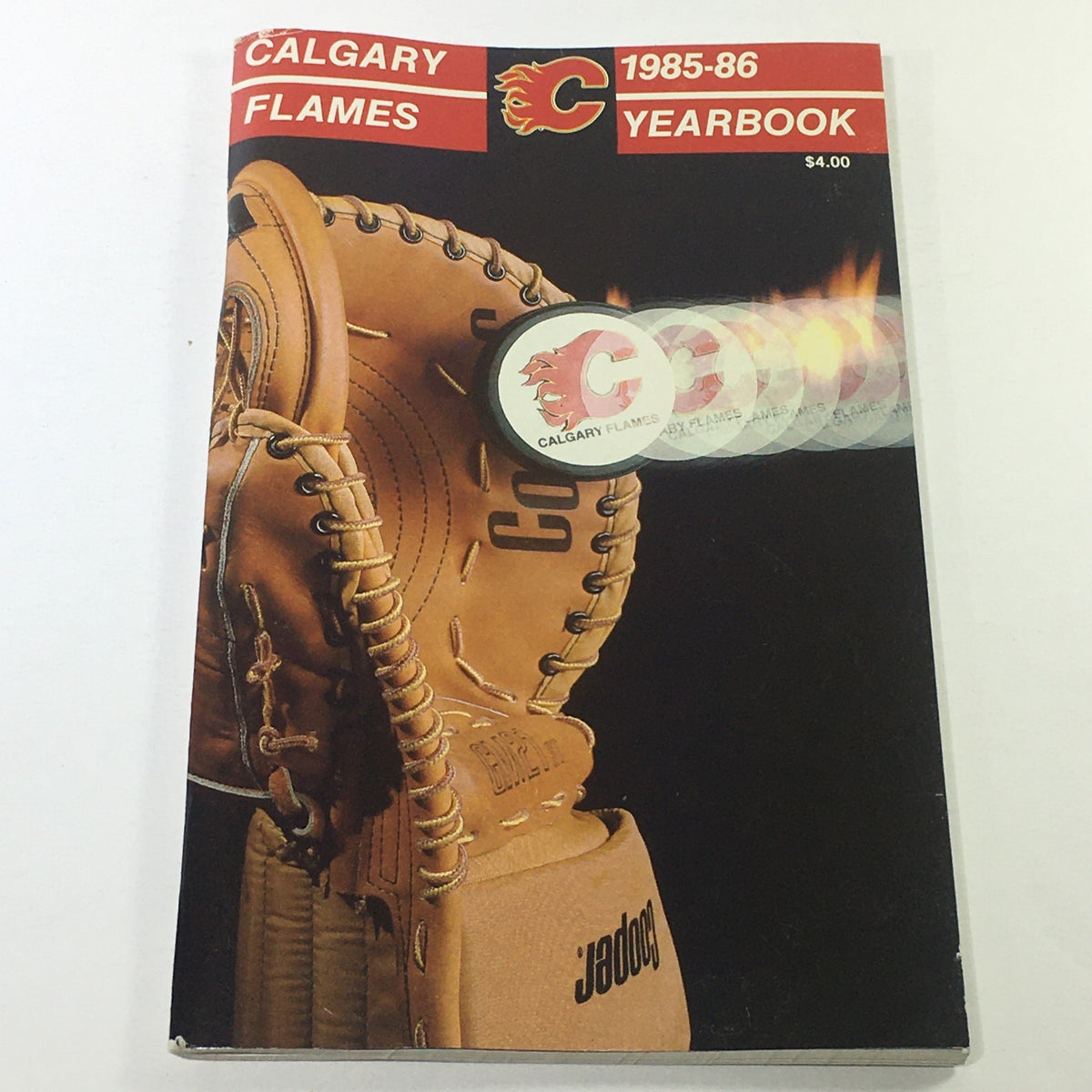 VTG NHL Official Yearbook 1985-1986 featuring Calgary Flames, showcasing a hockey glove with a burning hockey puck design, priced at $4.00.