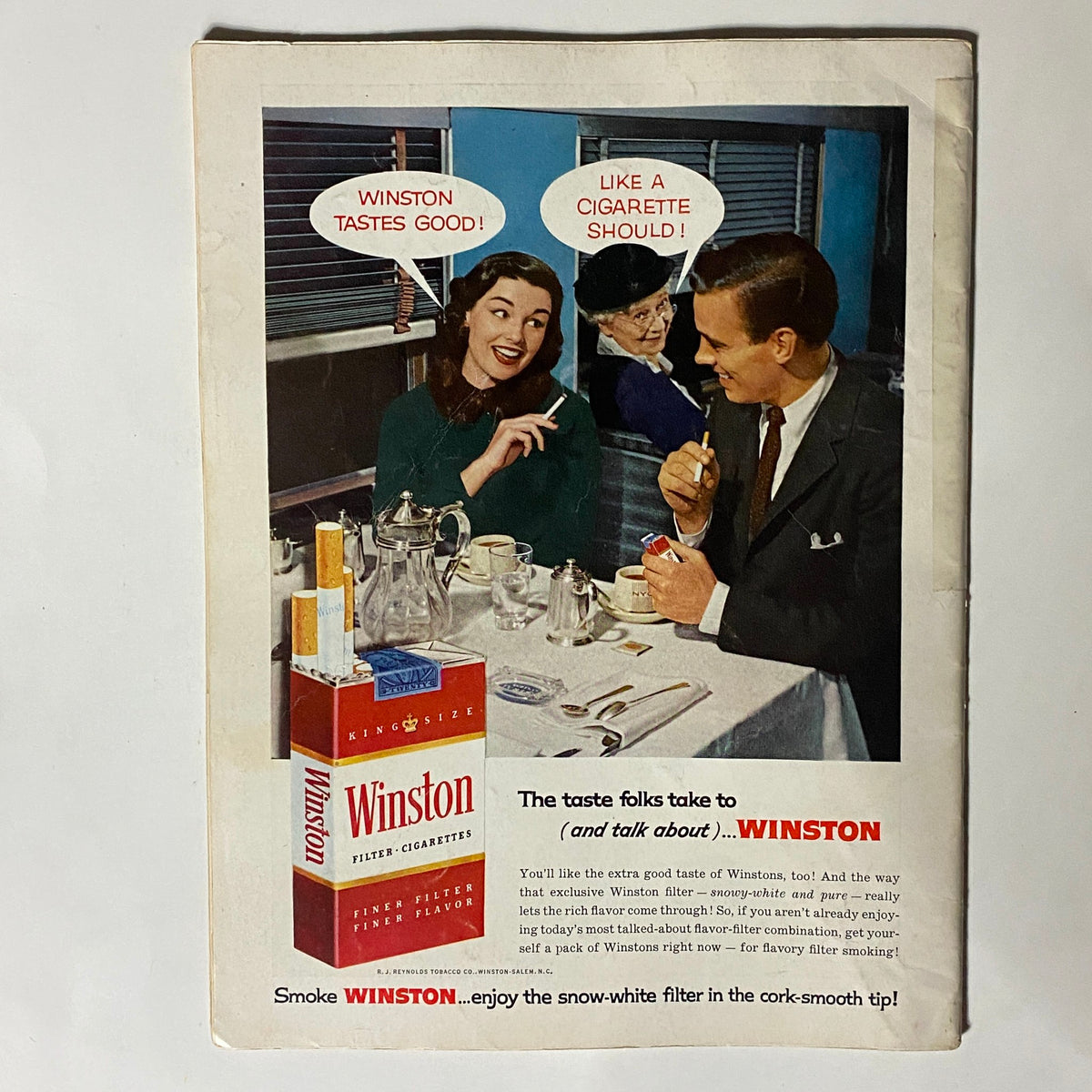 Vintage advertisement for Winston cigarettes featuring a stylish woman enjoying a cigarette at a dining table, with playful text promoting the brand. Part of the VTG Playboy Magazine April 1957, showcasing the era's charm.