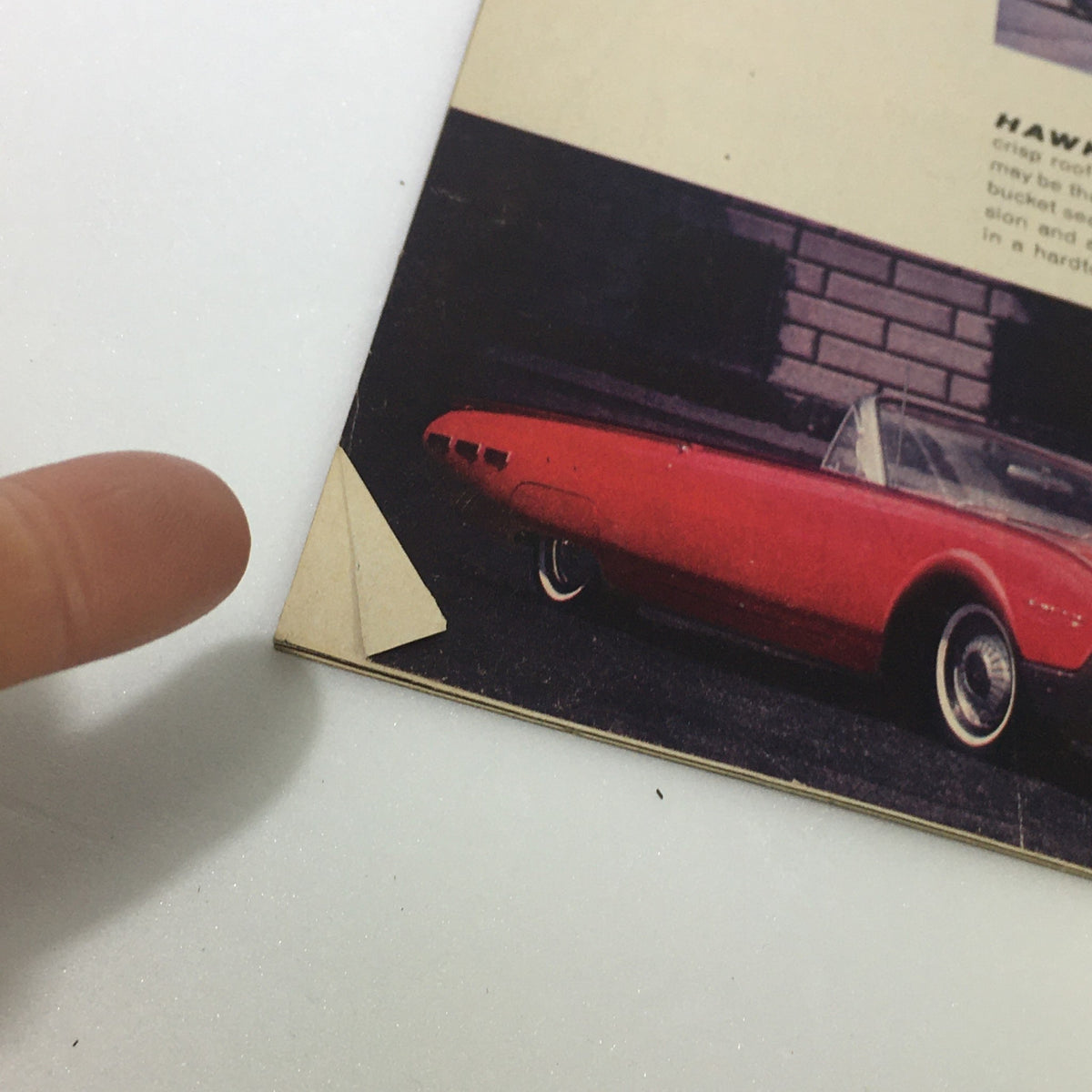 1962 Complete Magazine Guide To New Cars close-up showing the corner detail of the Hawk model with a finger pointing at the page.