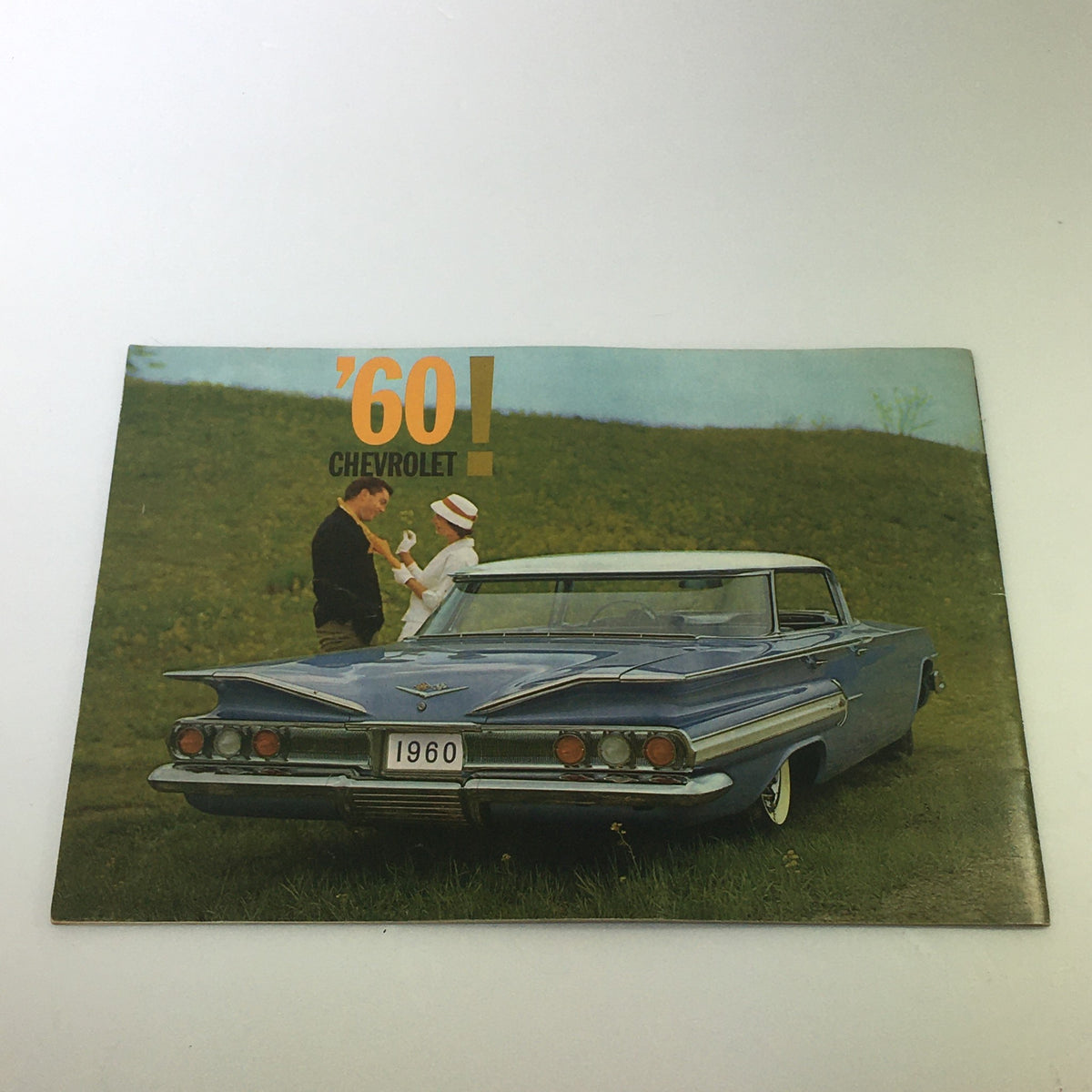 VTG 1960 Chevrolet Space Spirit Splendor Car Auto Brochure showcasing a blue Chevrolet parked in a scenic landscape, with a couple interacting, symbolizing the charm of 1960s car elegance.