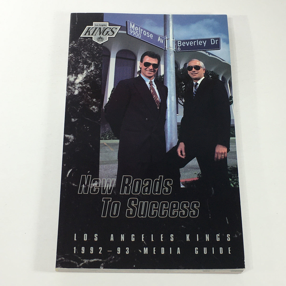 VTG NHL Official Media Guide 1992-1993 - Los Angeles Kings featuring Barry Melrose, showcasing two men in suits standing outside a building.