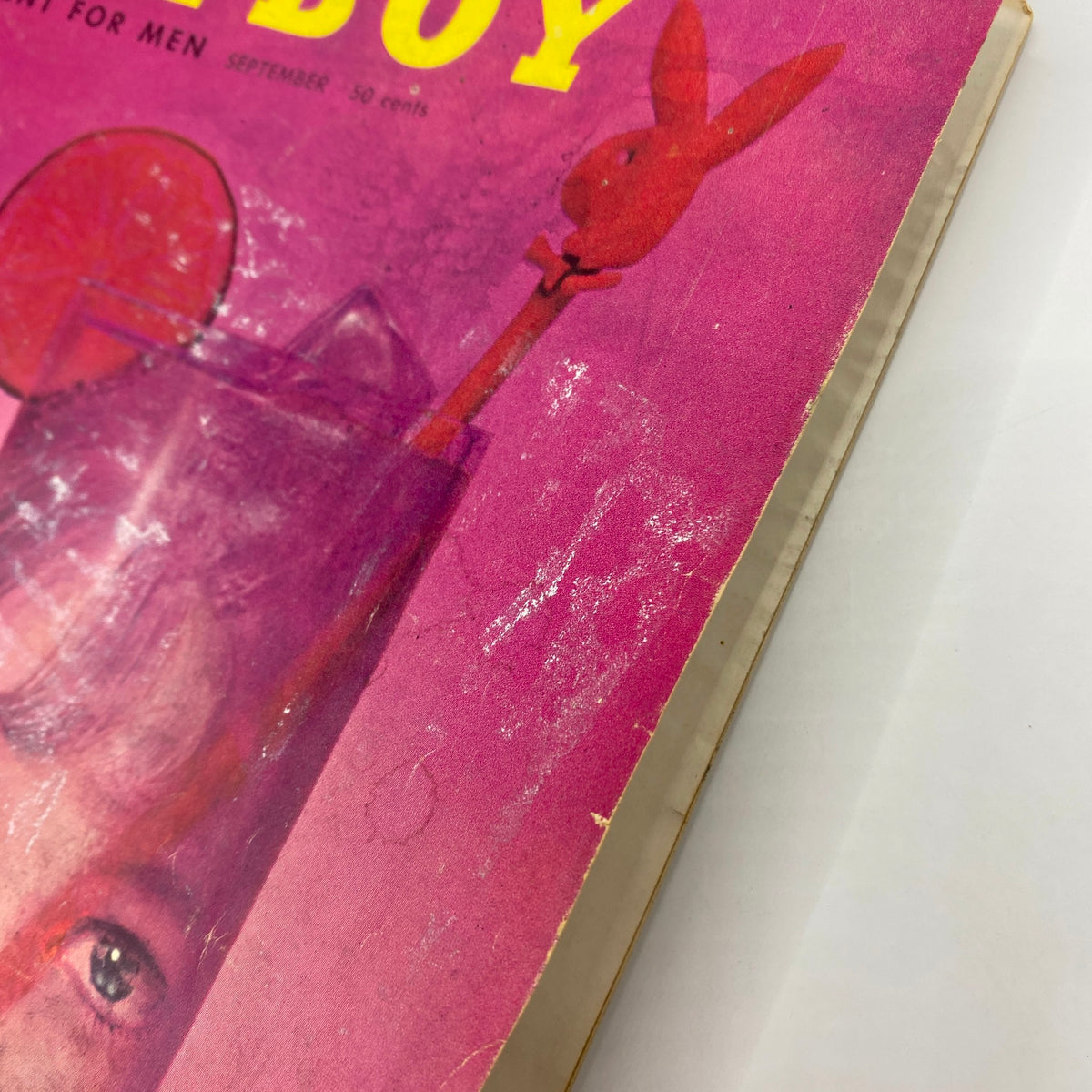Close-up of the cover of Playboy Magazine September 1957, highlighting the iconic pink background and detailing of the woman's face and Playboy bunny logo.