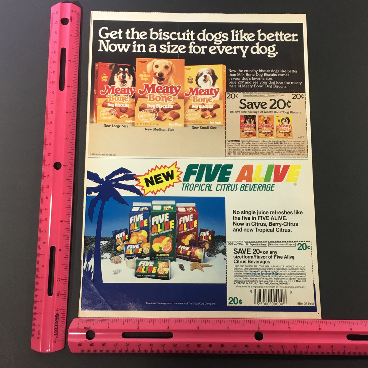 Side-by-side view of the Vintage 1985 Meaty Bone Dog Biscuits and Five Alive Tropical Beverage ad with a ruler for size reference, promoting dog treats and a refreshing drink.