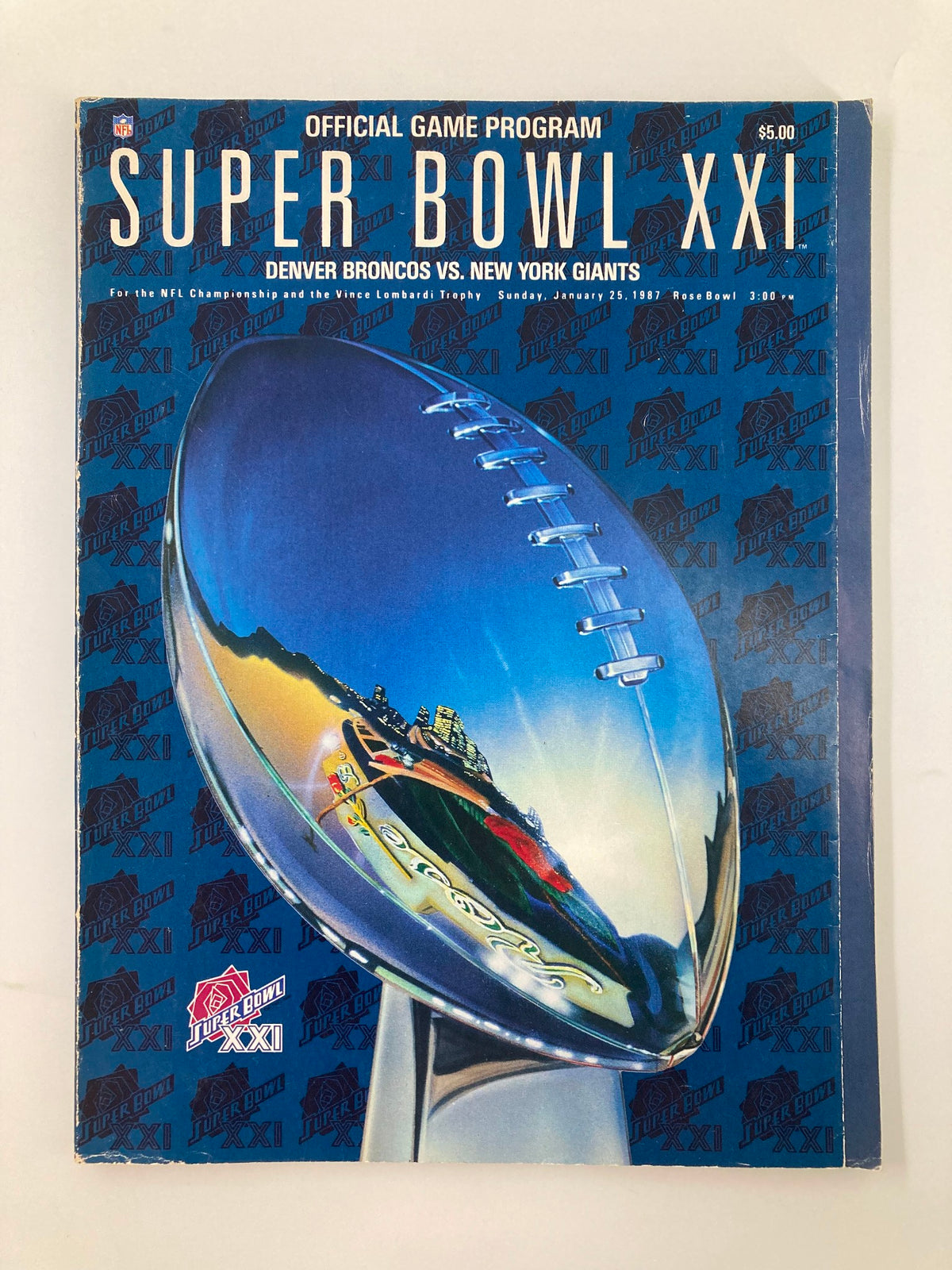 Official game program for Super Bowl XXI featuring the Denver Broncos vs. New York Giants, dated January 25, 1987. The cover showcases a vibrant design with a football trophy and striking blue background.