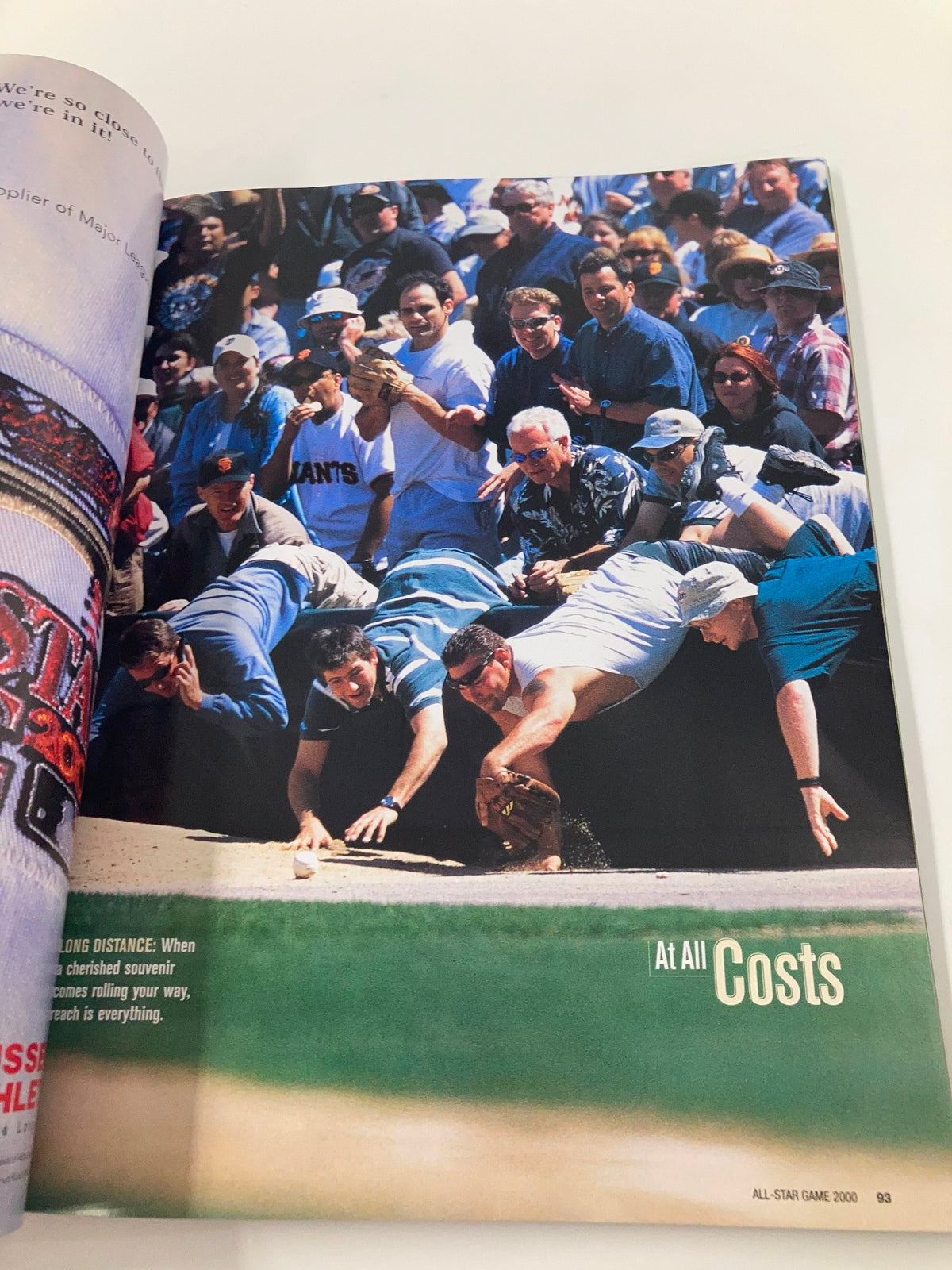 Image from the 2000 Major League Basketball All Star Game Official Program, displaying passionate fans reaching for a baseball, highlighting the excitement of the event.