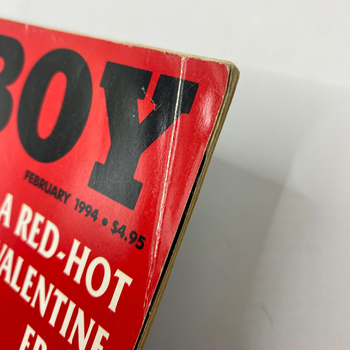 Close-up of the spine of Playboy Magazine February 1994 showing the edge damage and price tag, indicating its vintage condition.