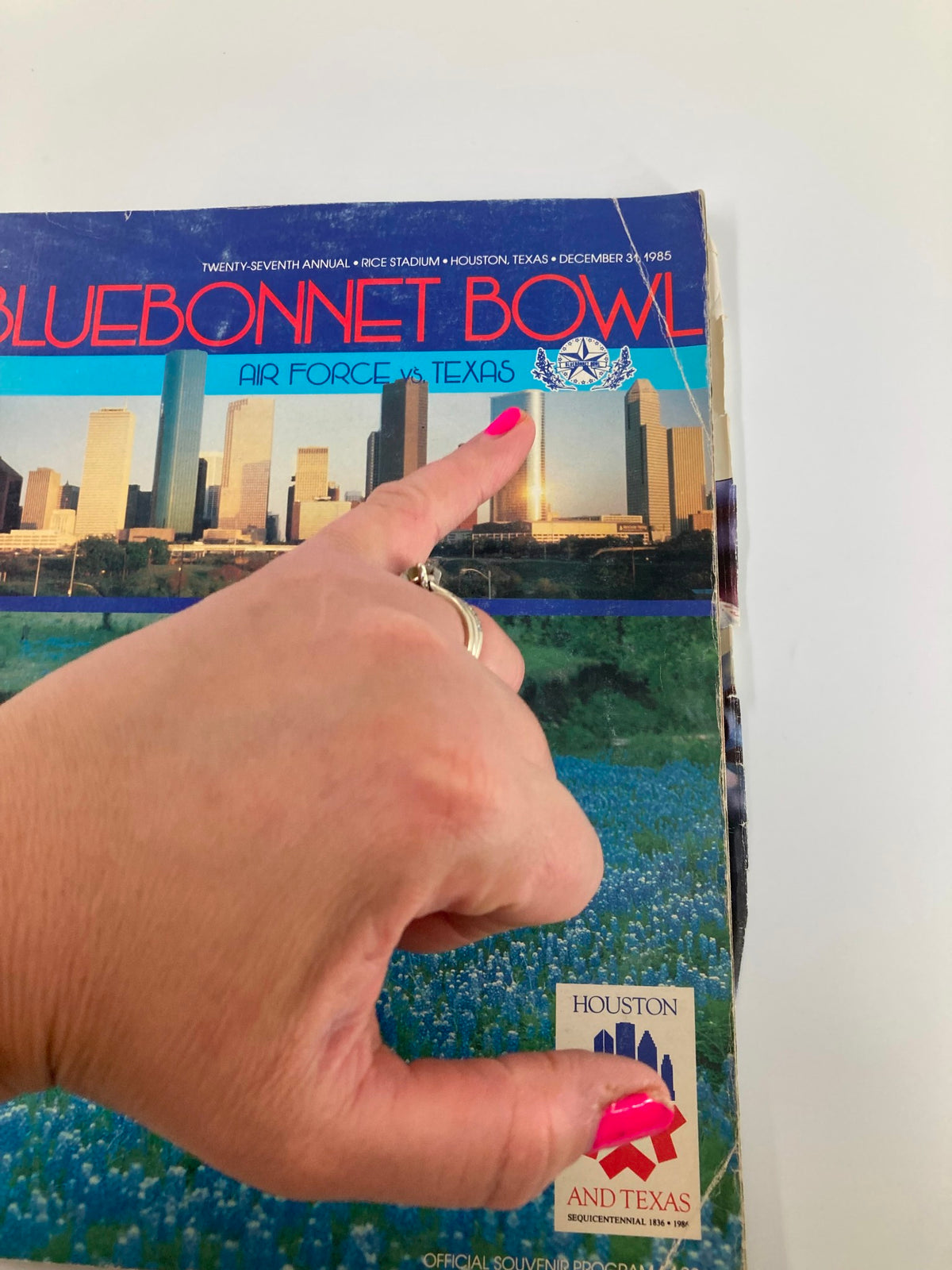Detail of VTG December 31 1985 Air Force vs Texas Bluebonnet Bowl Official Program cover with a hand pointing to the title.