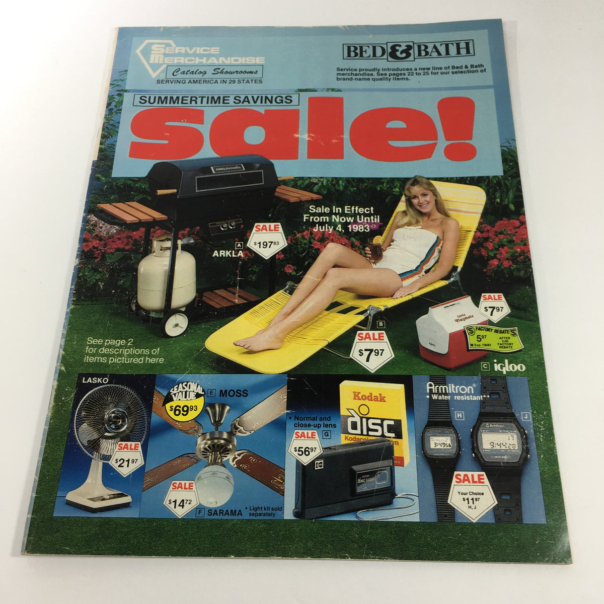 VTG 1983 Service Merchandise Catalog Showroom Summertime Savings Sale Guide featuring a promotional cover with a woman relaxing in a yellow lounge chair, a grill, and sale items including fans and a cooler, showcasing summer products.