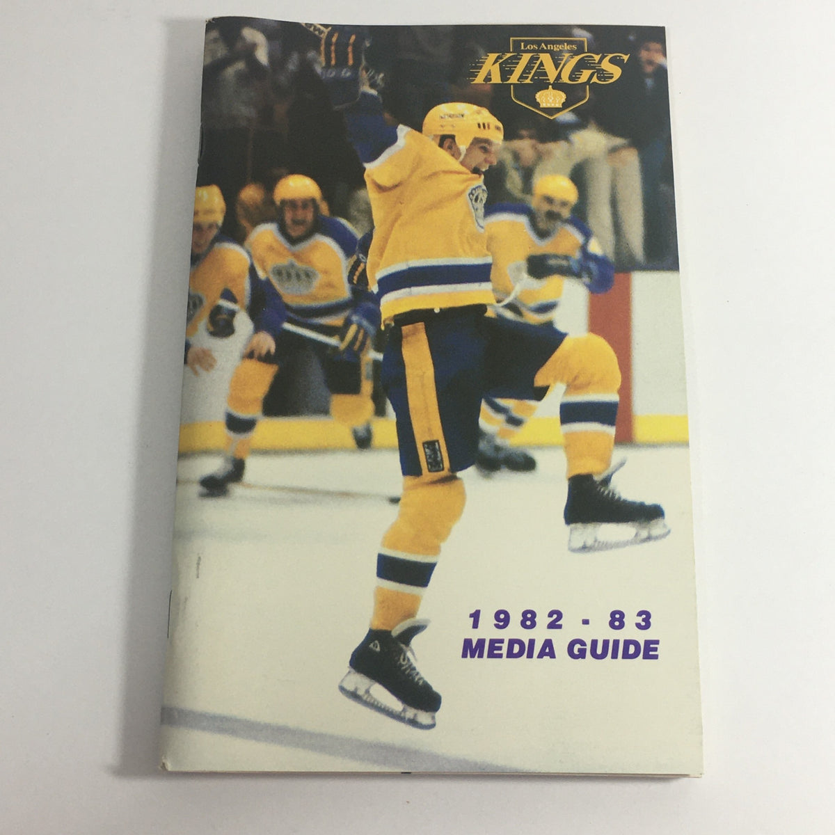 Cover of the VTG NHL Official Media Guide 1982-1983 - Los Angeles Kings featuring Steve Bozek celebrating a goal with teammates in yellow uniforms.