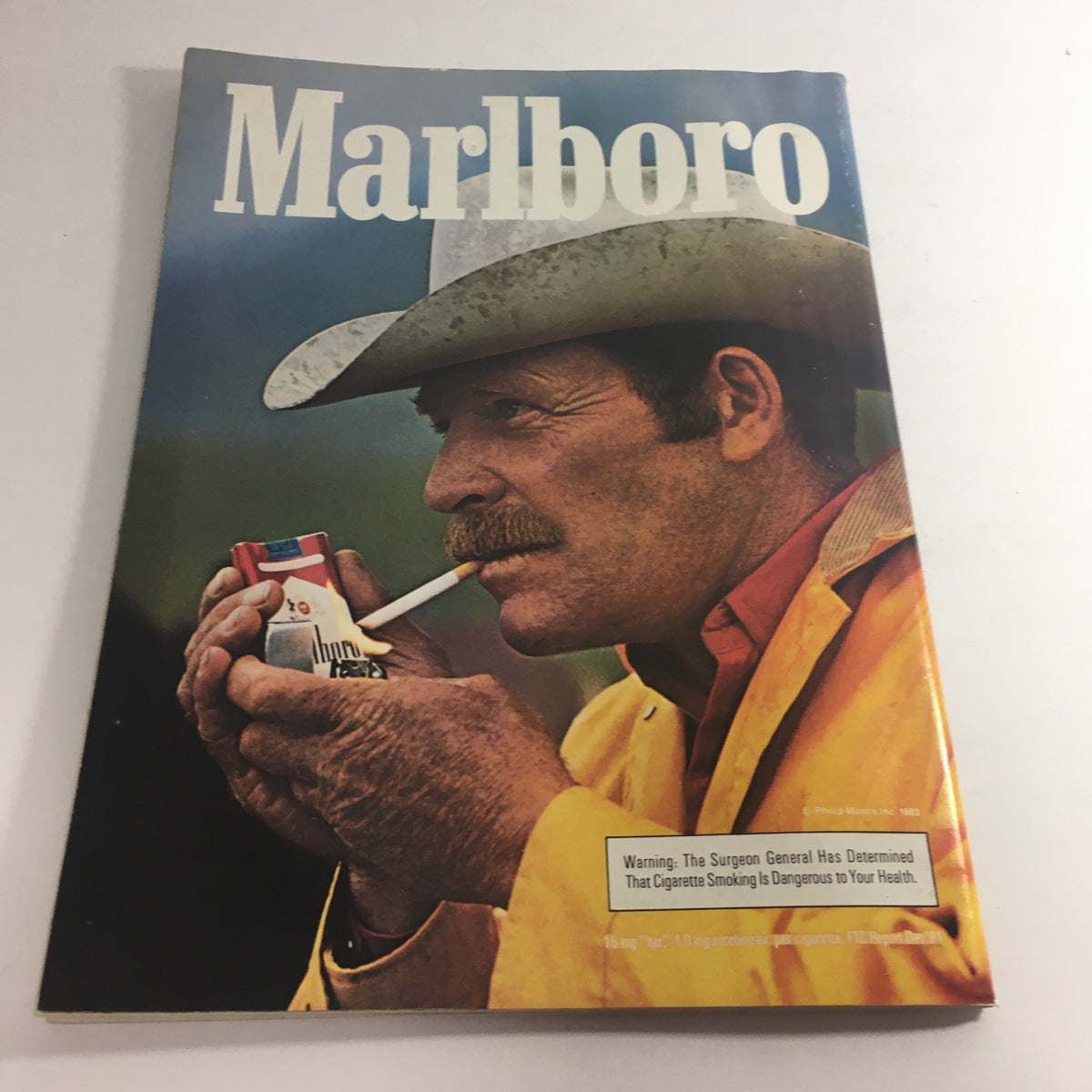 Cover of a vintage Marlboro magazine from 1983, portraying a man in a cowboy hat holding a cigarette, emphasizing the product branding.