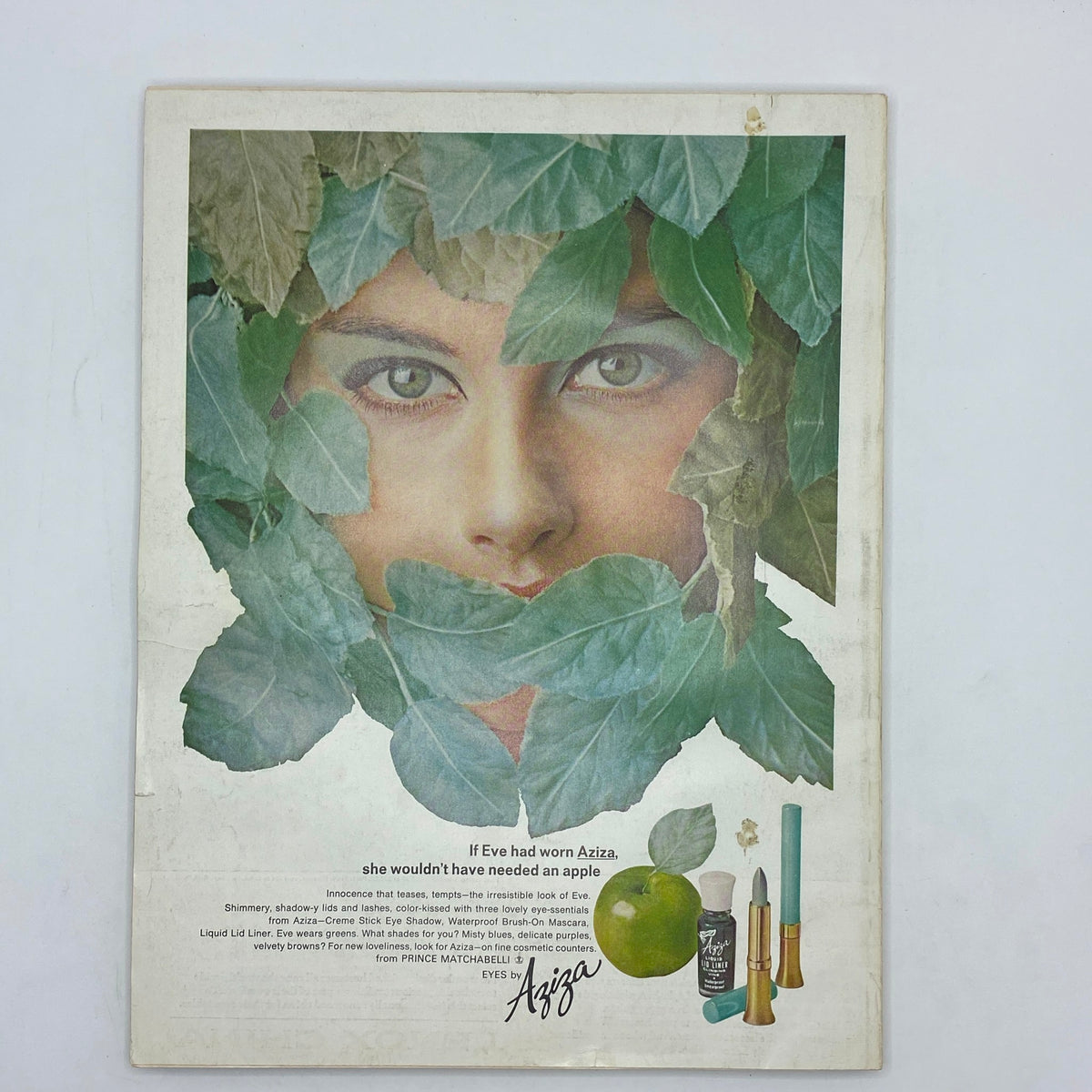 Vintage advertisement from VTG Vogue Magazine March 1 1966 showcasing a model's face framed by green leaves, advertising Aziza cosmetics. This unique ad reflects the beauty trends of the 60s with a creative emphasis on natural elements.