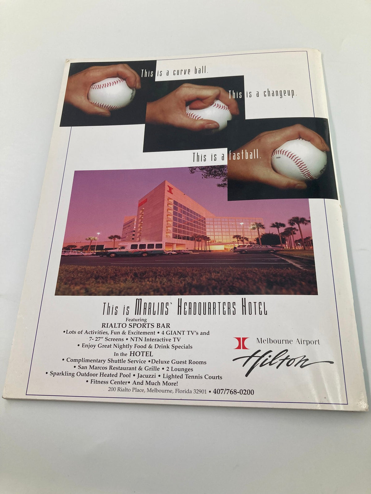 1997 Spring Training Space Coast Stadium Brevard County Program featuring a baseball-themed advertisement for Hilton, showcasing sports activities and amenities with images of baseballs labeled as curveball, changeup, and fastball.