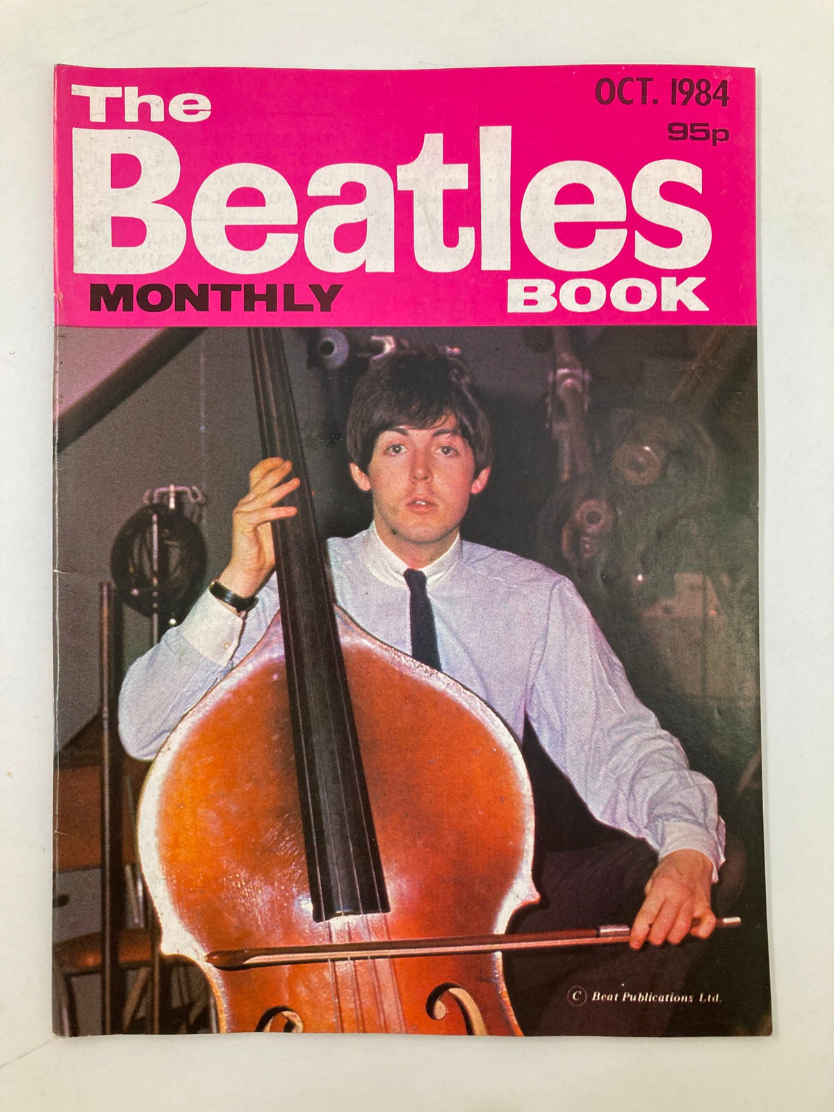 Cover of The Beatles Book Monthly Magazine October 1984 #102 featuring Paul McCartney playing double bass, with a vibrant pink and white design.