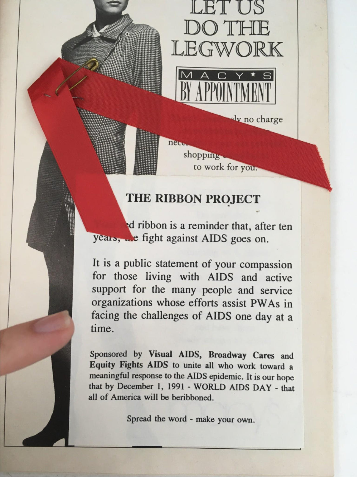 A detailed image of a 1991 Playbill for Cats Nine Forever by Cameron Mackintosh featuring a red ribbon associated with The Ribbon Project, promoting awareness and support for those affected by AIDS.