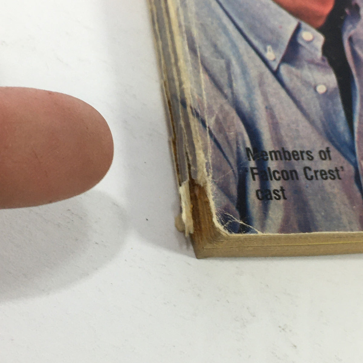 Close-up image of a finger pointing at the edge of the VTG TV Guide Magazine May 22-28, 1982, highlighting the presence of members of the cast from 'Falcon Crest'.
