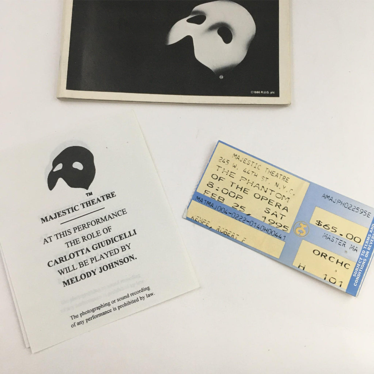 Close-up view of 1995 Playbill Phantom of the Opera, Davis Gaines Harold Prince, Majestic Theatre featuring a ticket and performance card related to the show.