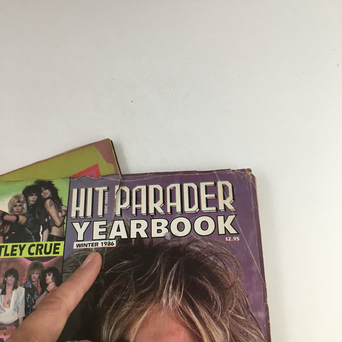 Cover of Hit Parader Yearbook Winter 1986 featuring a hand pointing to the title and part of the magazine's cover showcasing Motley Crue.