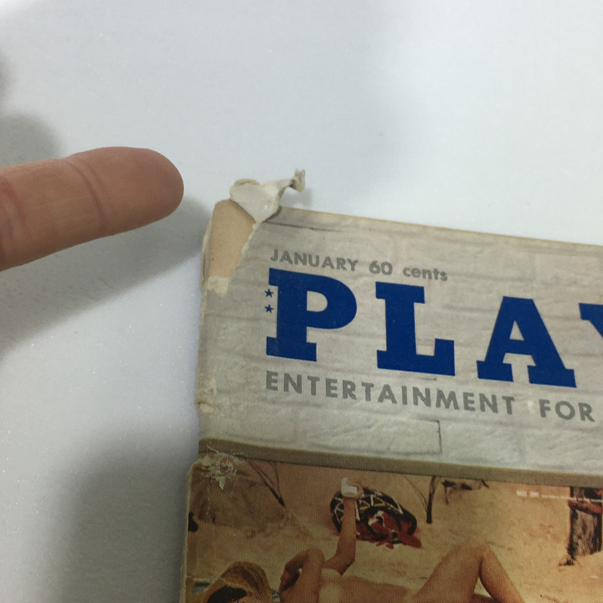 Close-up of the damaged corner of the VTG Playboy Magazine January 1961 Vol. 8 #1, showing wear and tear typical of vintage magazines.