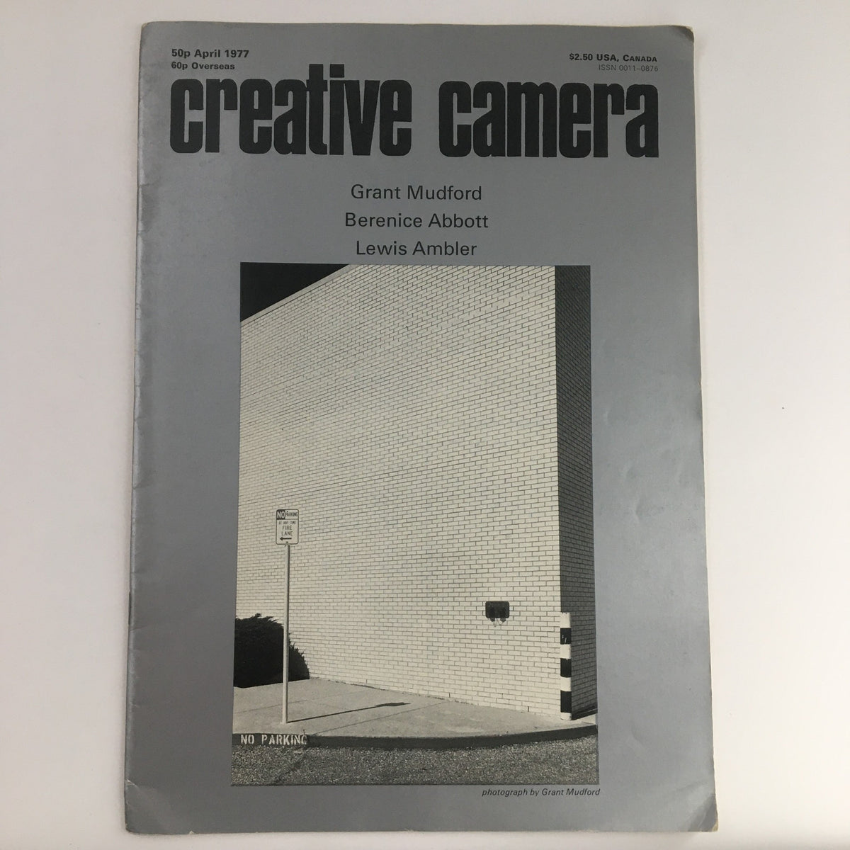 Creative Camera Magazine April 1977 featuring contributions from Grant Mufford, Berenice Abbott, and Lewis Ambler. The magazine cover showcases a minimalist design with a photograph of a wall and a no parking sign.