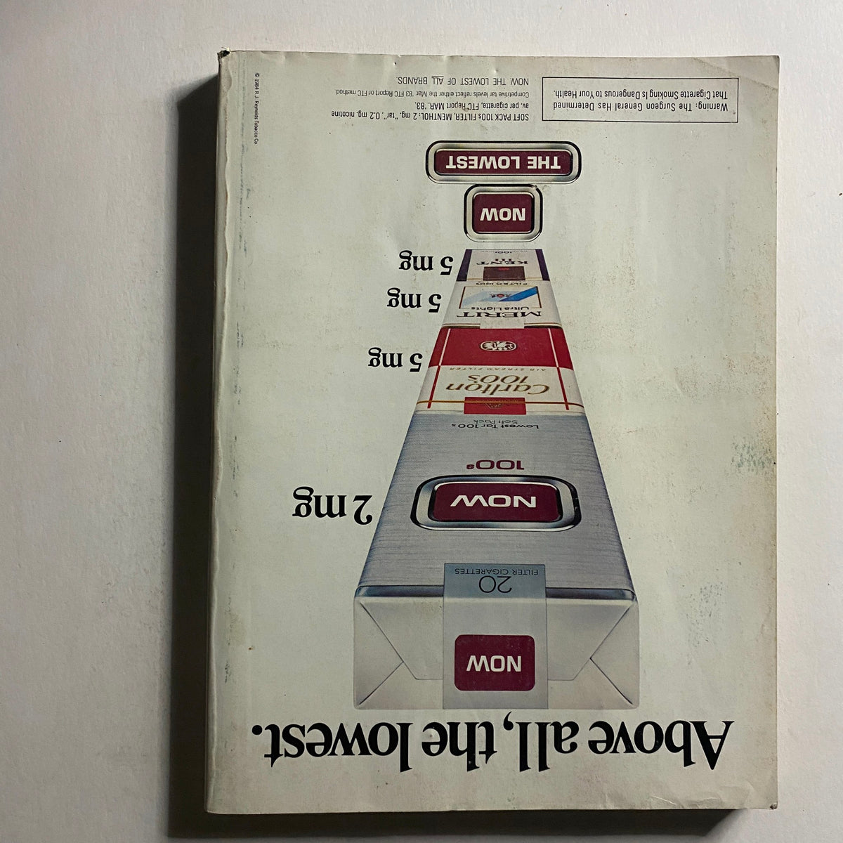 Back cover of VTG Vogue Magazine March 1984 showcasing advertising for 'Now The Lowest' products with a simple design and striking text.