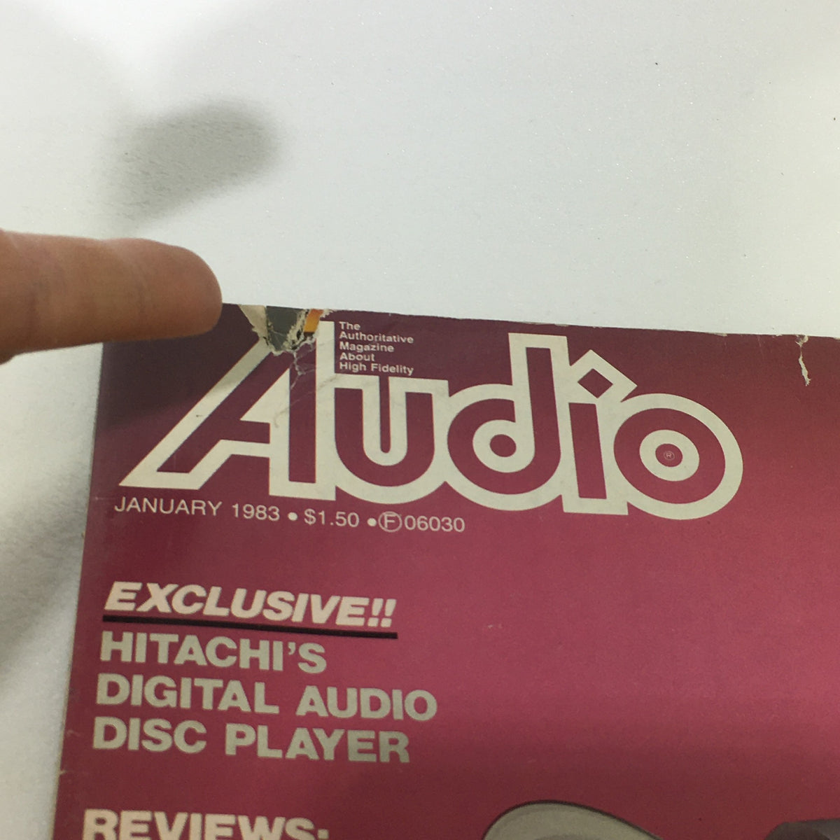 Close-up of the damaged corner of the Audio and Music Magazine, January 1983, highlighting the title and features like Hitachi's Digital Audio Disc Player.