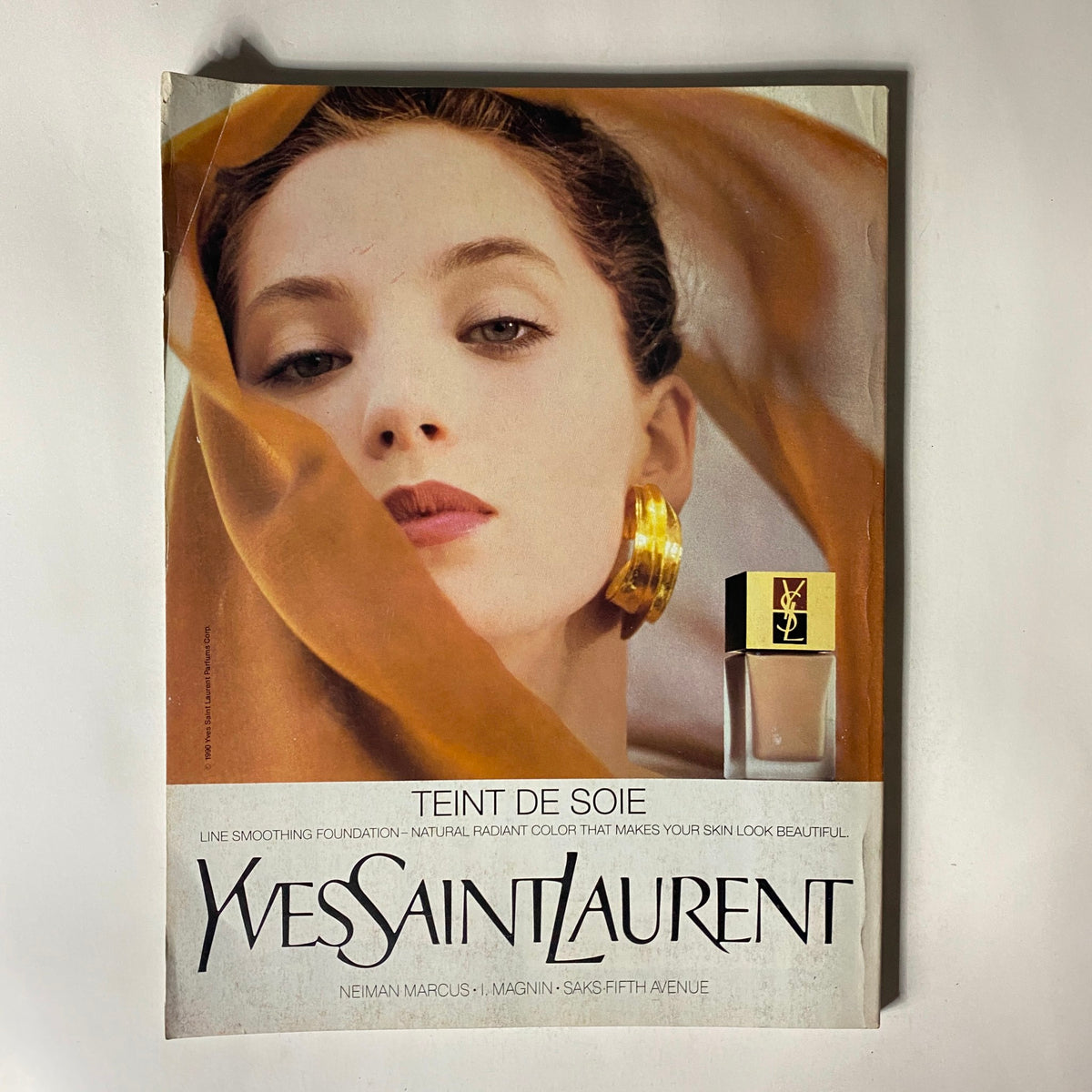 Vogue Magazine January 1991 featuring a captivating advertisement for Yves Saint Laurent, displaying a model with elegant styling and golden accessories, promoting a foundation product.
