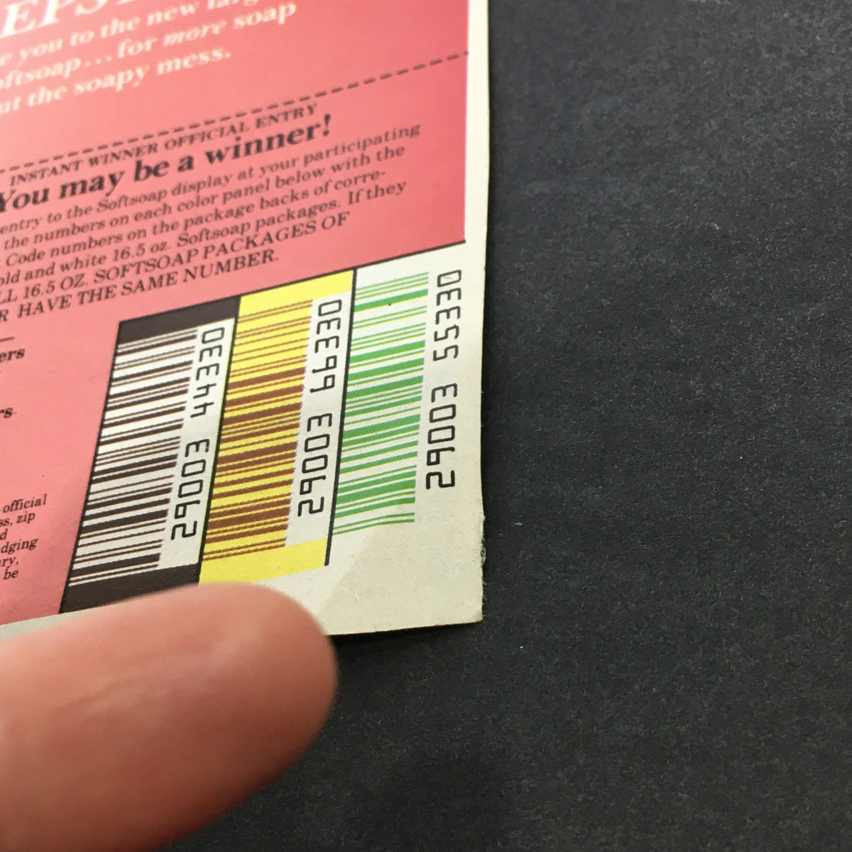 Close-up view of the 1981 Softsoap Soft Life Sweepstakes coupon, featuring colorful sections and a finger pointing to important details, showcasing the VTG Retro ad with the title 'VTG Retro 1981 Softsoap Soft Life Sweepstakes No Soapy Mess Store Ad Coupon'.