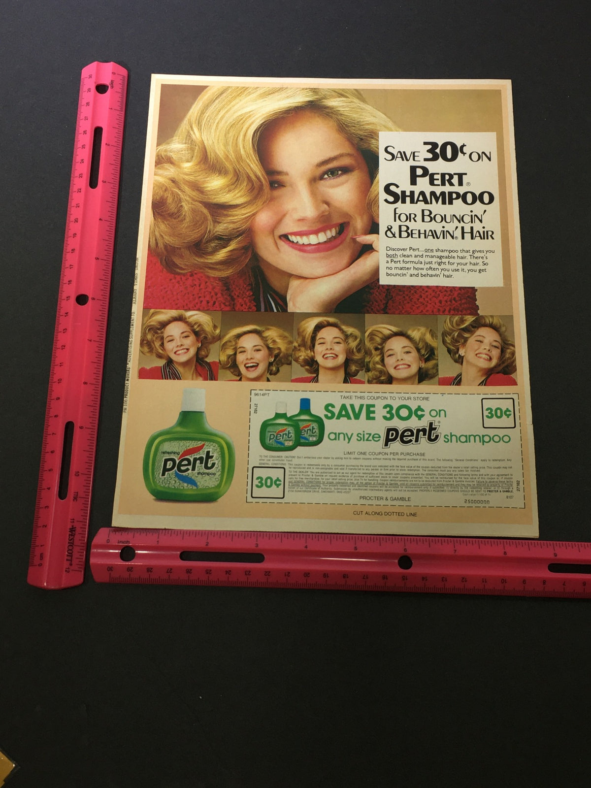 Close-up view of the VTG 1980 Pert Refreshing Shampoo For Bouncin' & Behavin' Hair Print Ad with a ruler for size reference, displaying a coupon for $0.30 off Pert shampoo.