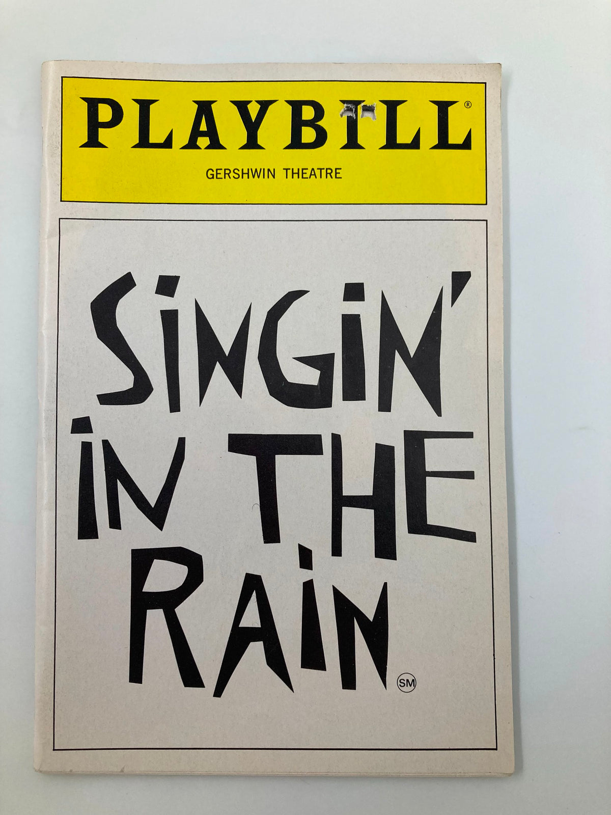 Cover of the 1986 Playbill for 'Singin' In The Rain' at the Gershwin Theatre, showcasing bold black lettering.