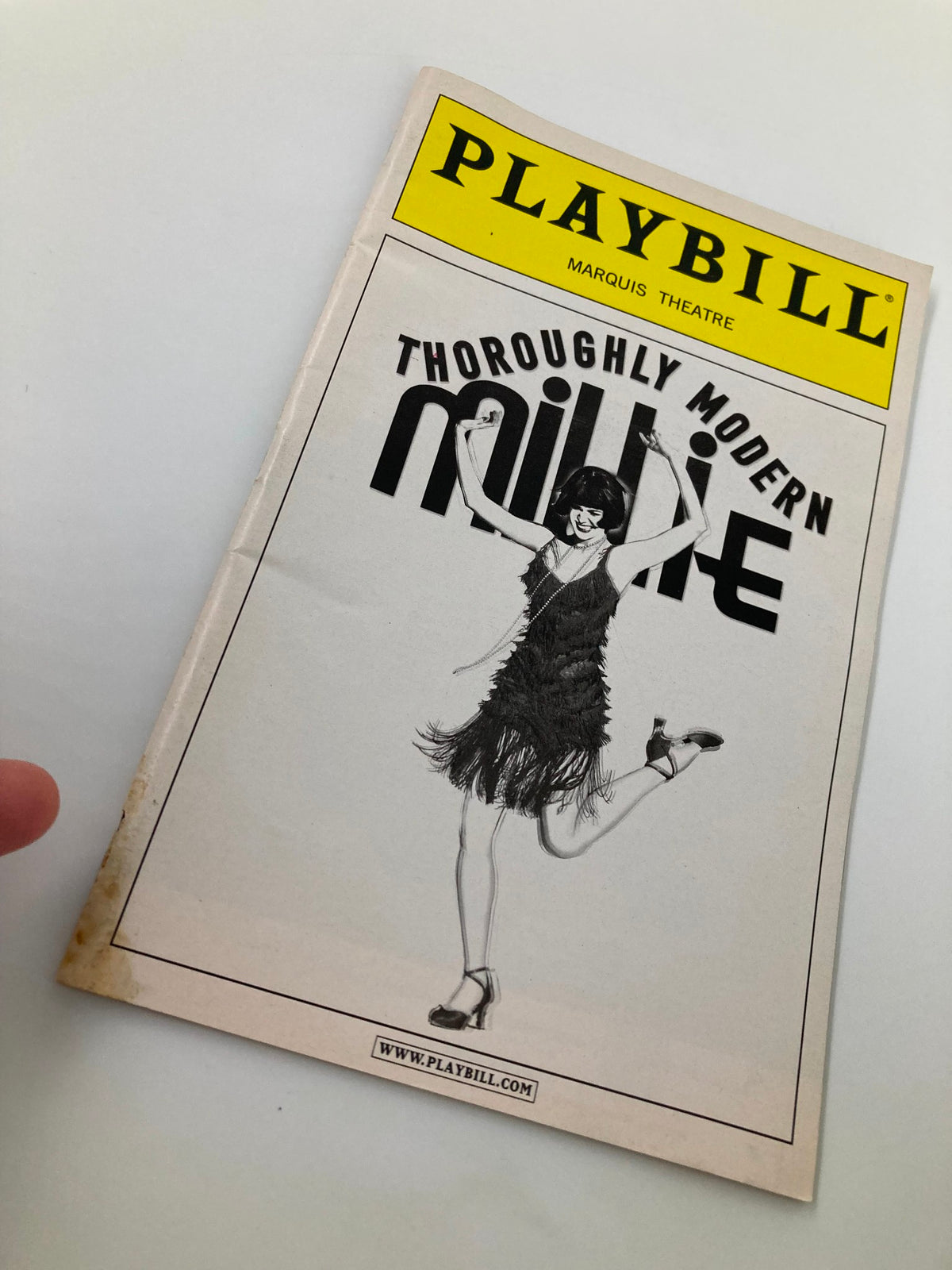 2002 Playbill for Thoroughly Modern Millie at the Marquis Theatre with a close-up image showcasing the iconic cover and dancer illustration.