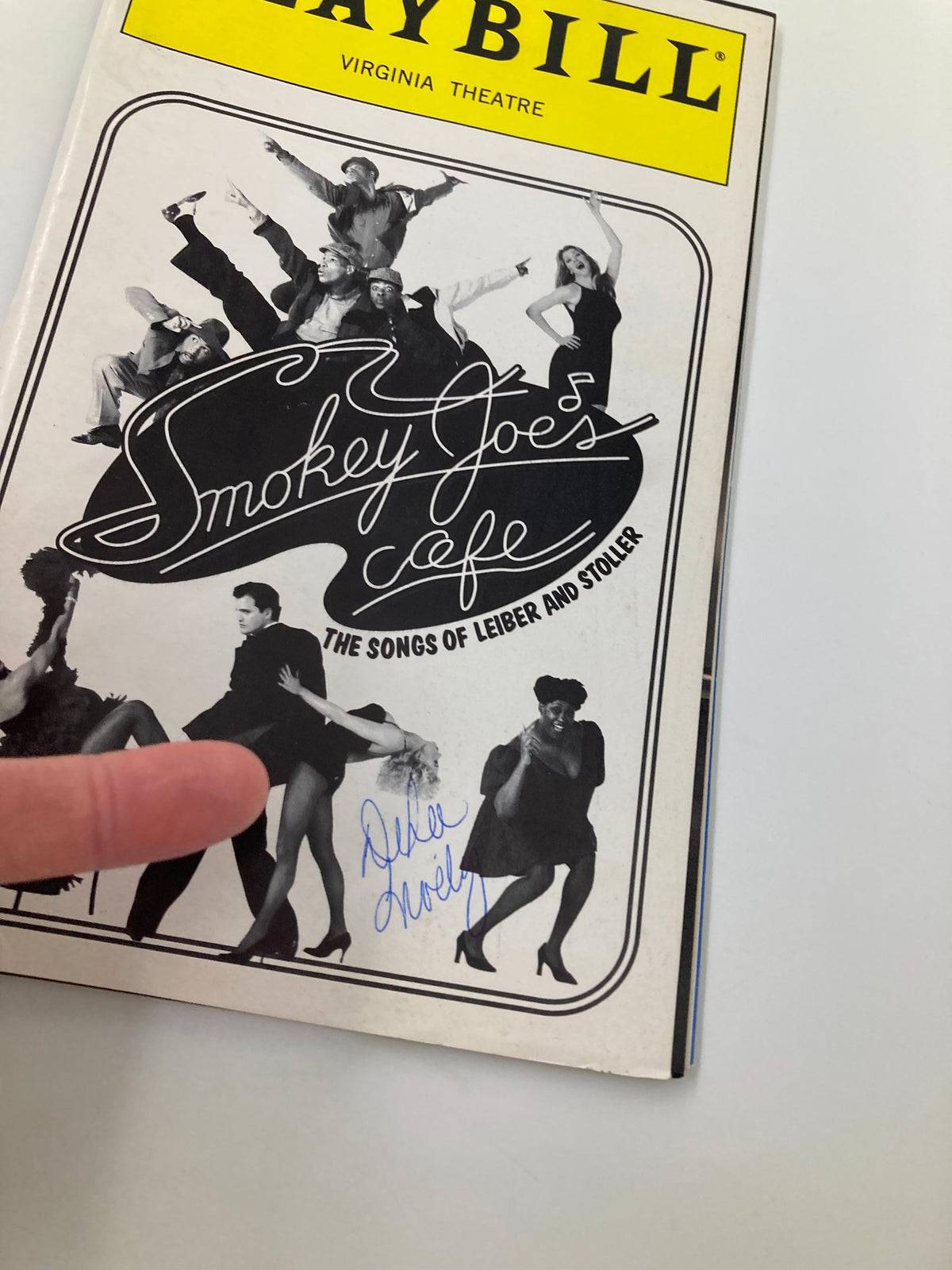 Close-up view of the 1996 Playbill for Smokey Joe's Cafe: The Songs of Leiber and Stoller, highlighting the front cover and a visible autograph.
