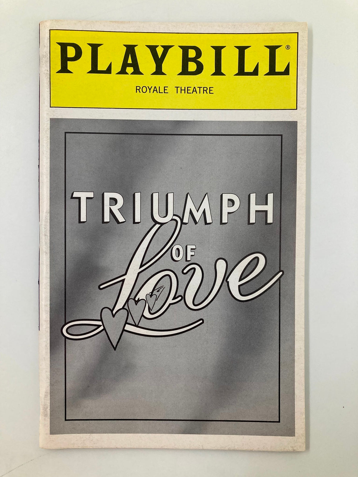 1997 Playbill for 'Triumph of Love' at the Royale Theatre, featuring an elegant cover design with hearts.