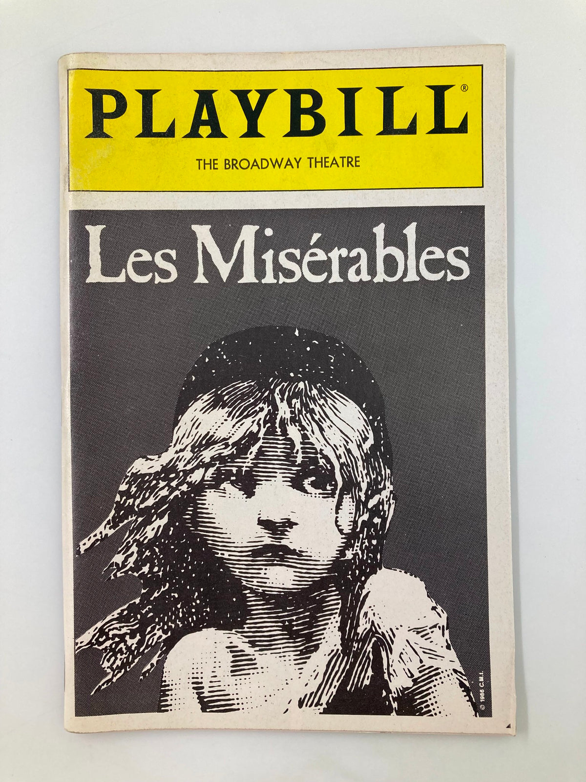 Cover of the 1989 Playbill for Les Miserables, featuring iconic artwork of the character Cosette against a stark black background, showcasing the title in elegant typography.