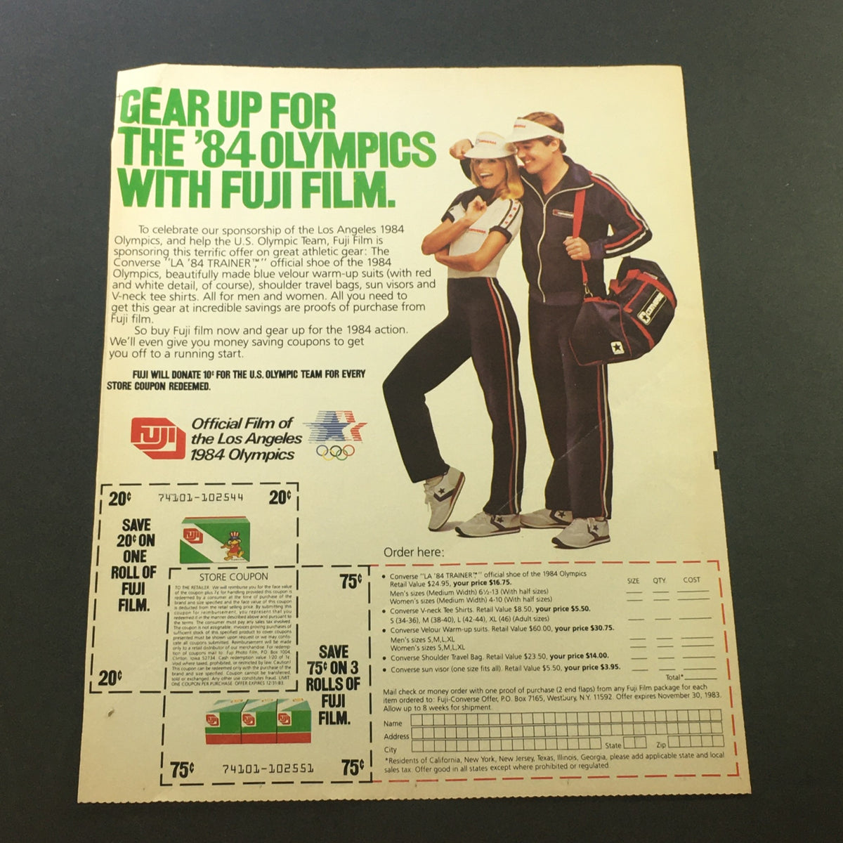 Vintage 1983 Fuji Official Film advertisement for the Los Angeles 1984 Olympics featuring models in Olympic gear, showcasing a store coupon and promotional offers for athletic apparel.