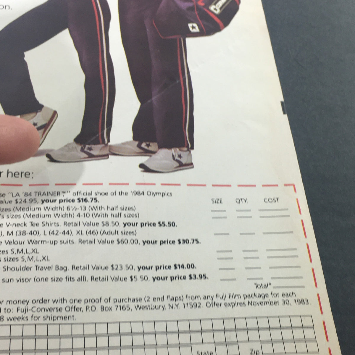 Image of the reverse side of the VTG 1983 - Fuji Official Film of the Los Angeles 1984 Olympics Store Ad Coupon, featuring pricing details for Olympic-themed apparel and products.