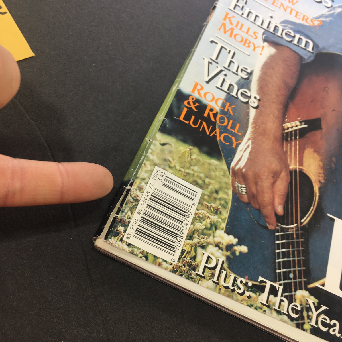 Close-up of the back cover of Rolling Stone Magazine Issue 903 from August 22, 2002 featuring Bruce Springsteen. The image shows a finger pointing to a mark on the magazine, highlighting its vintage condition. This issue captures important moments in music history.