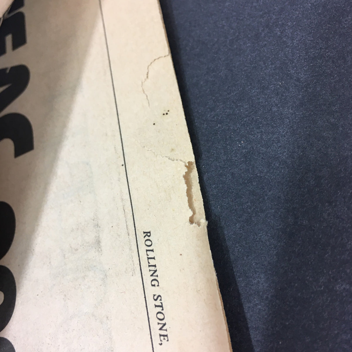 Close-up of the edge of the VTG Rolling Stone Magazine August 26 1976, showing minor wear and a small rip, emphasizing its vintage condition.