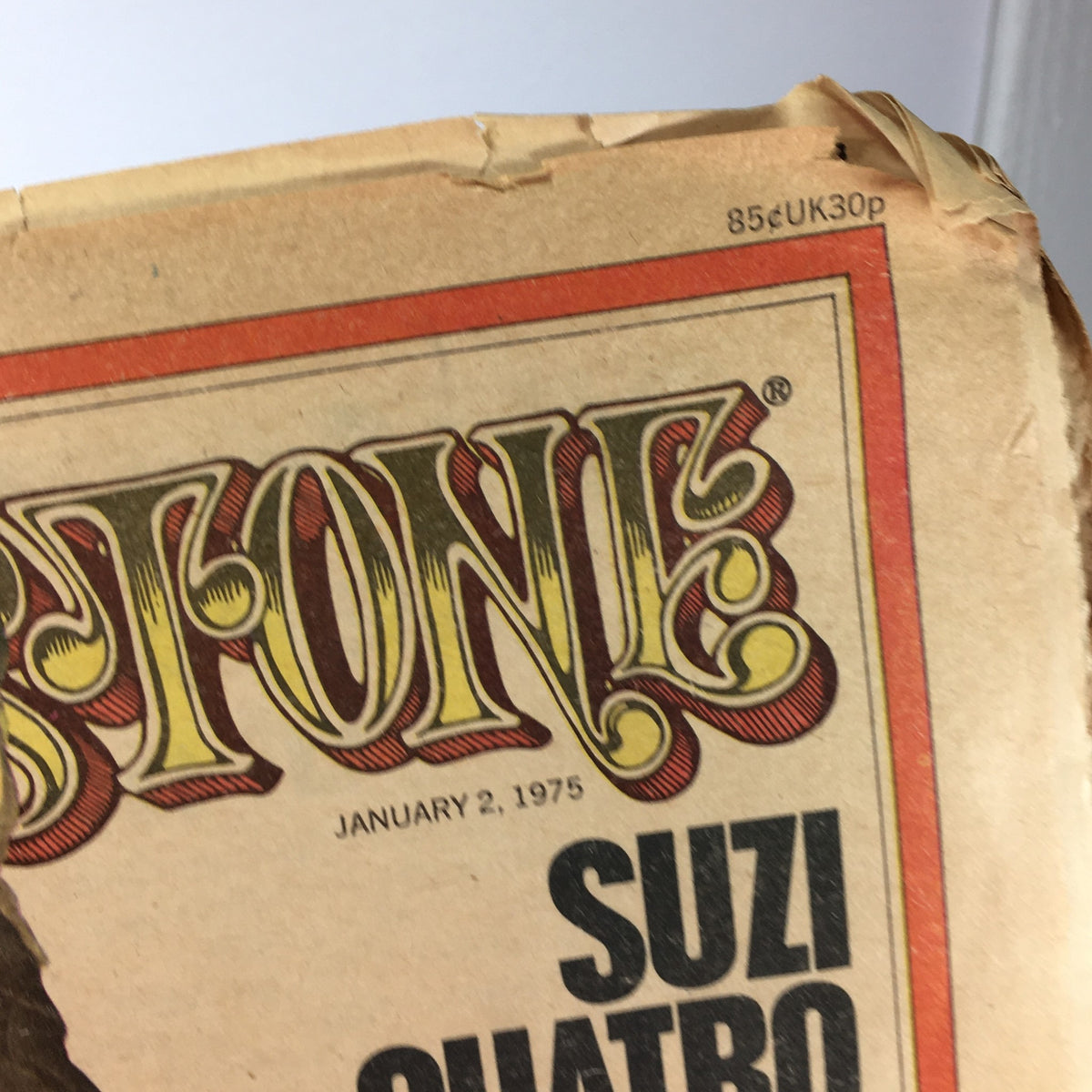 Detail of the top edge of the vintage Rolling Stone magazine from January 2, 1975, displaying the iconic magazine title and the issue date, along with the featured artist Suzi Quatro.