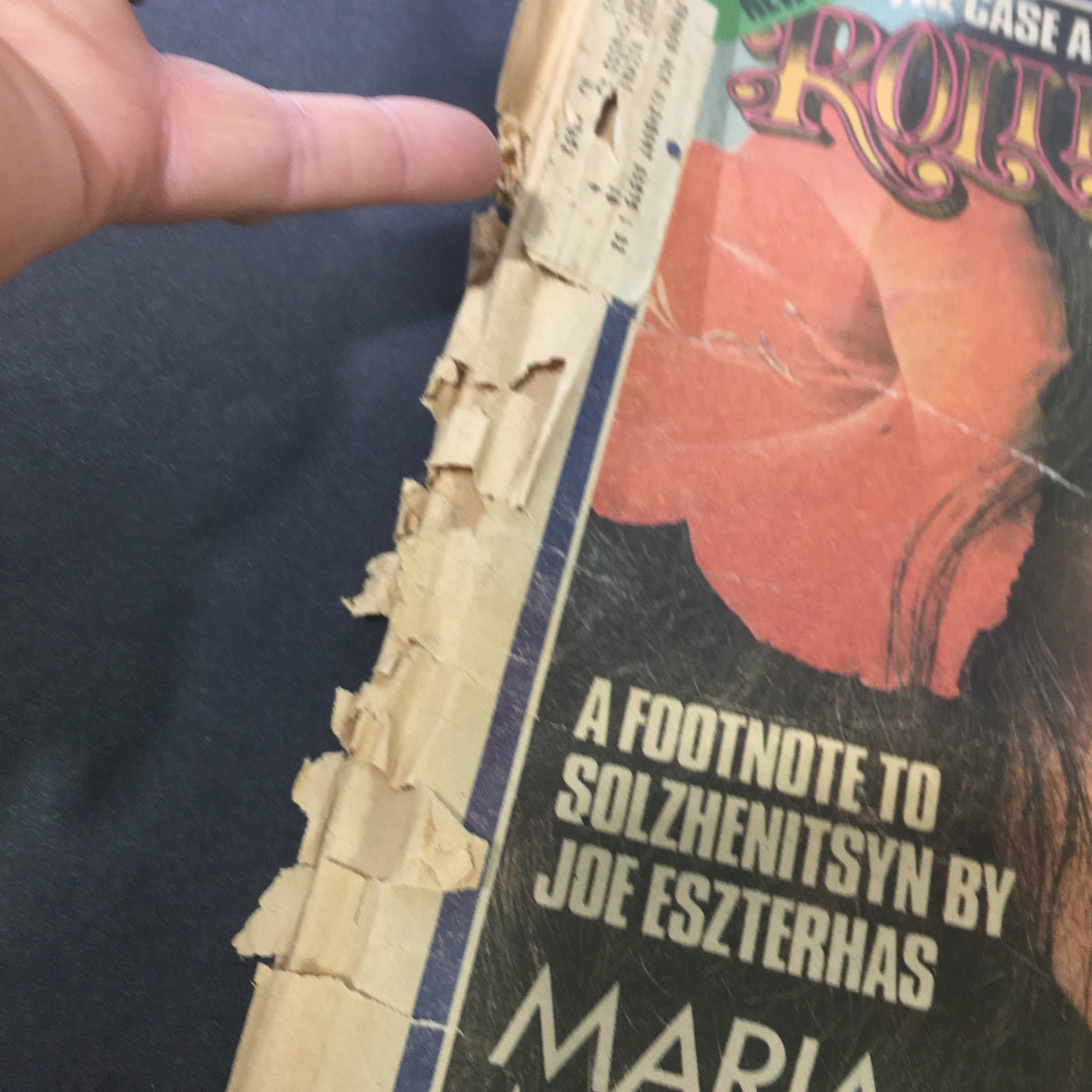 Close-up of the side view of the Vintage Rolling Stone Magazine August 1, 1974, highlighting wear and tear with a finger pointing to damaged edges of the cover.