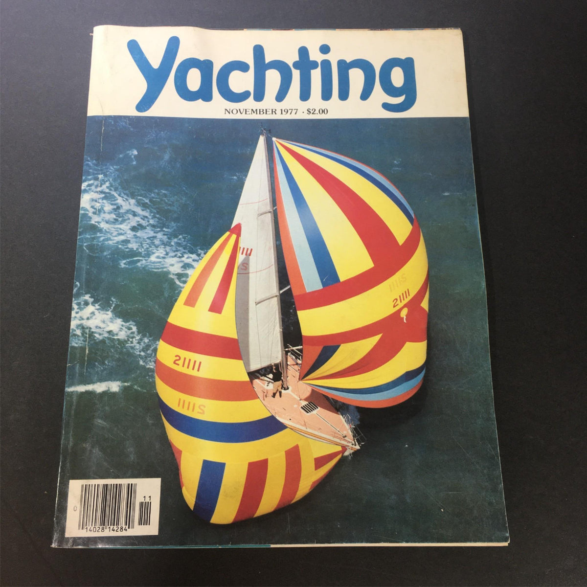 Cover of Vintage Yachting Magazine November 1977 featuring colorful sails and ocean background. A collectible issue that explores Alaska's microcosm and sailing adventure.