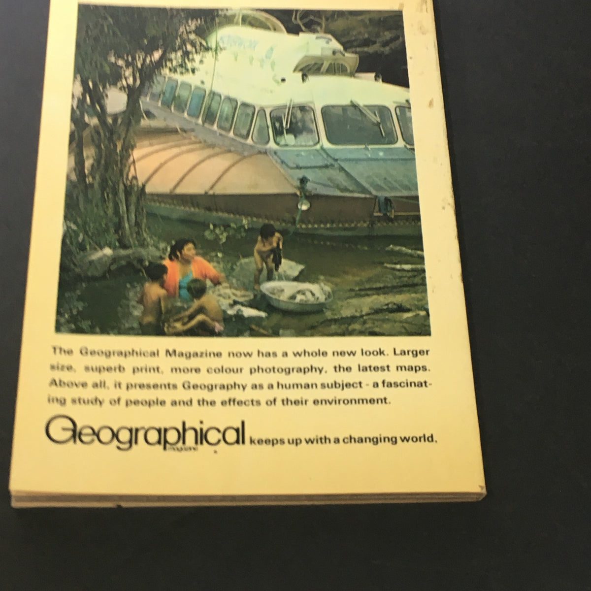 Back cover of a Geographical magazine showing a vintage boat and people engaging in activities by the water, emphasizing the magazine's theme of geography and environmental interaction.