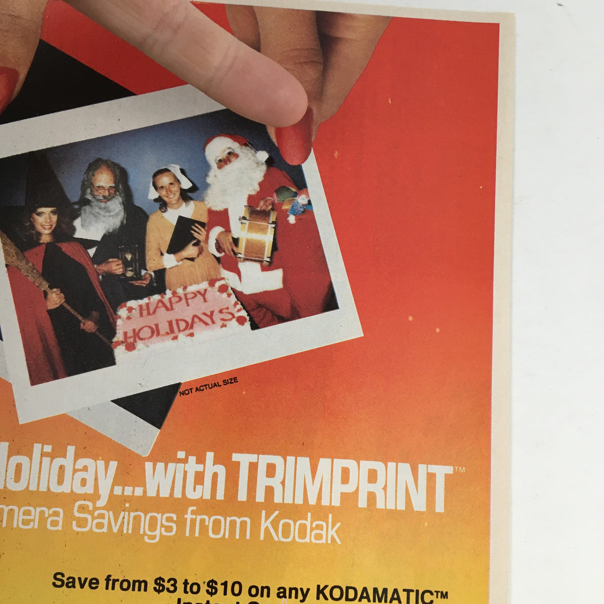 Close-up of the 1983 Kodamatic Instant Camera Circular Coupon Advertisement, showcasing a Kodak camera with holiday-themed imagery, including Santa Claus, emphasizing the holiday savings promotion.