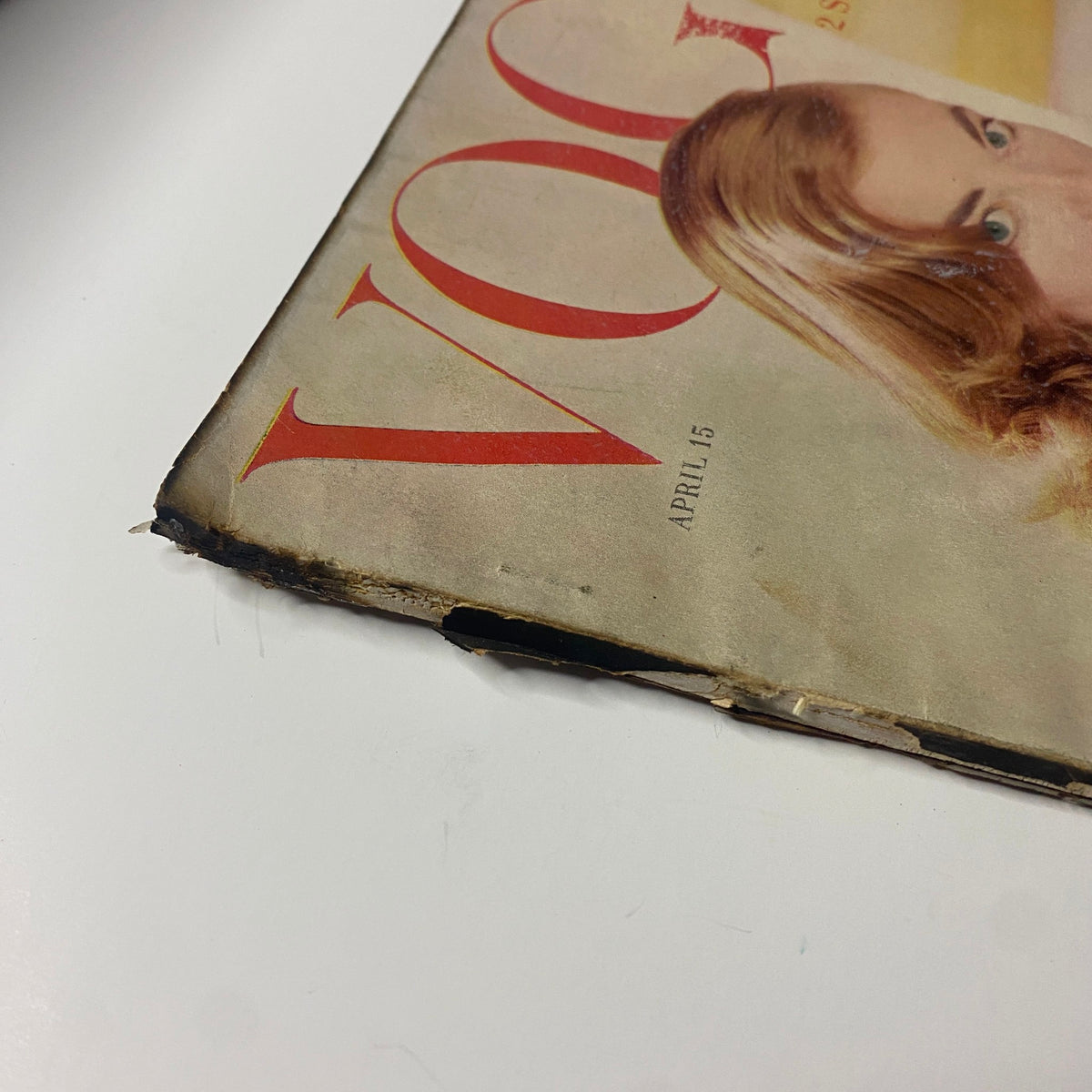 Close-up of the cover edge of Vogue Magazine April 15, 1955, highlighting wear and tear on the spine, showcasing the magazine's vintage character.