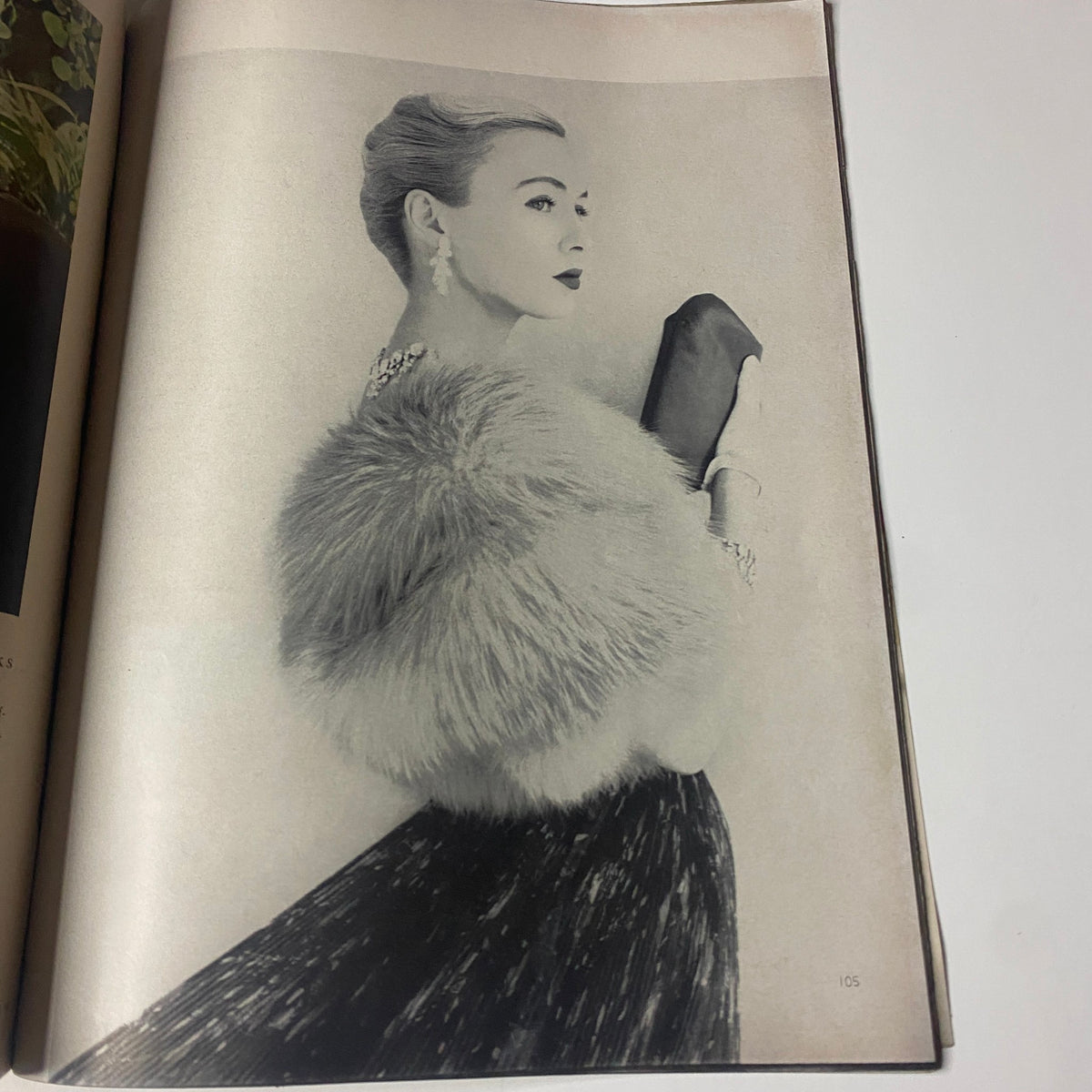 Elegant fashion illustration in Vogue Magazine April 15, 1955 featuring a woman in a luxurious fur wrap.