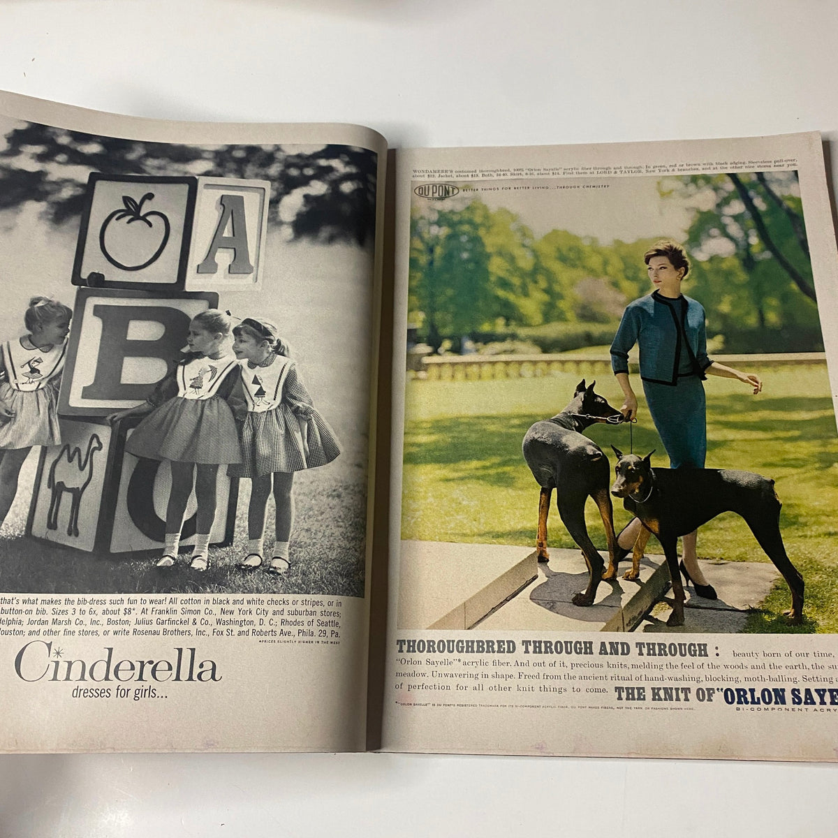 Interior spread from Vogue Magazine August 15, 1961 featuring a vintage photograph of young girls in dresses playing with alphabet blocks next to an advertisement highlighting the durability of Dupont's ORLON fabric, capturing mid-century childhood elegance.