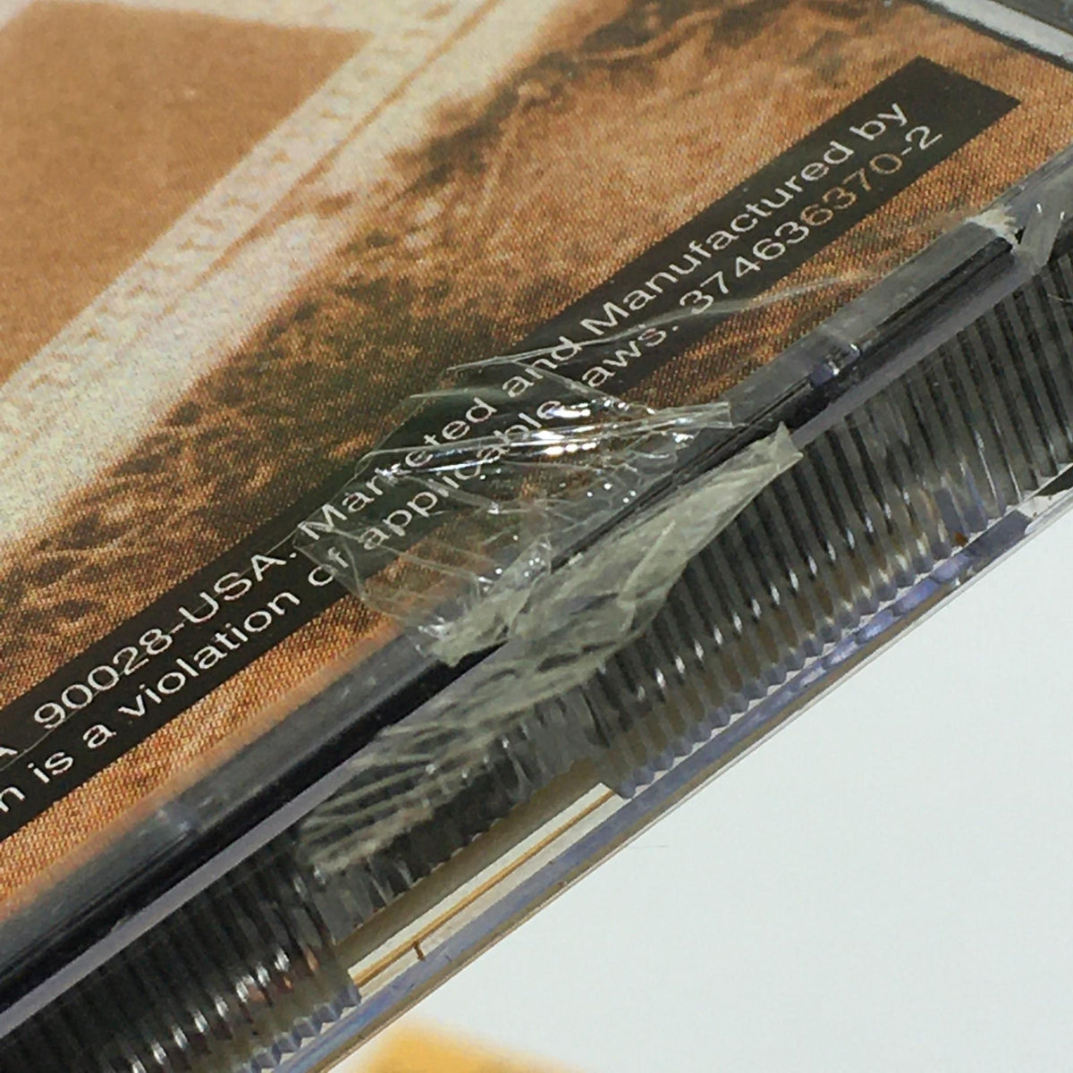 Close-up of damaged plastic case of Black Reign by Queen Latifah Music Audio CD, highlighting the slight rip near the hole.